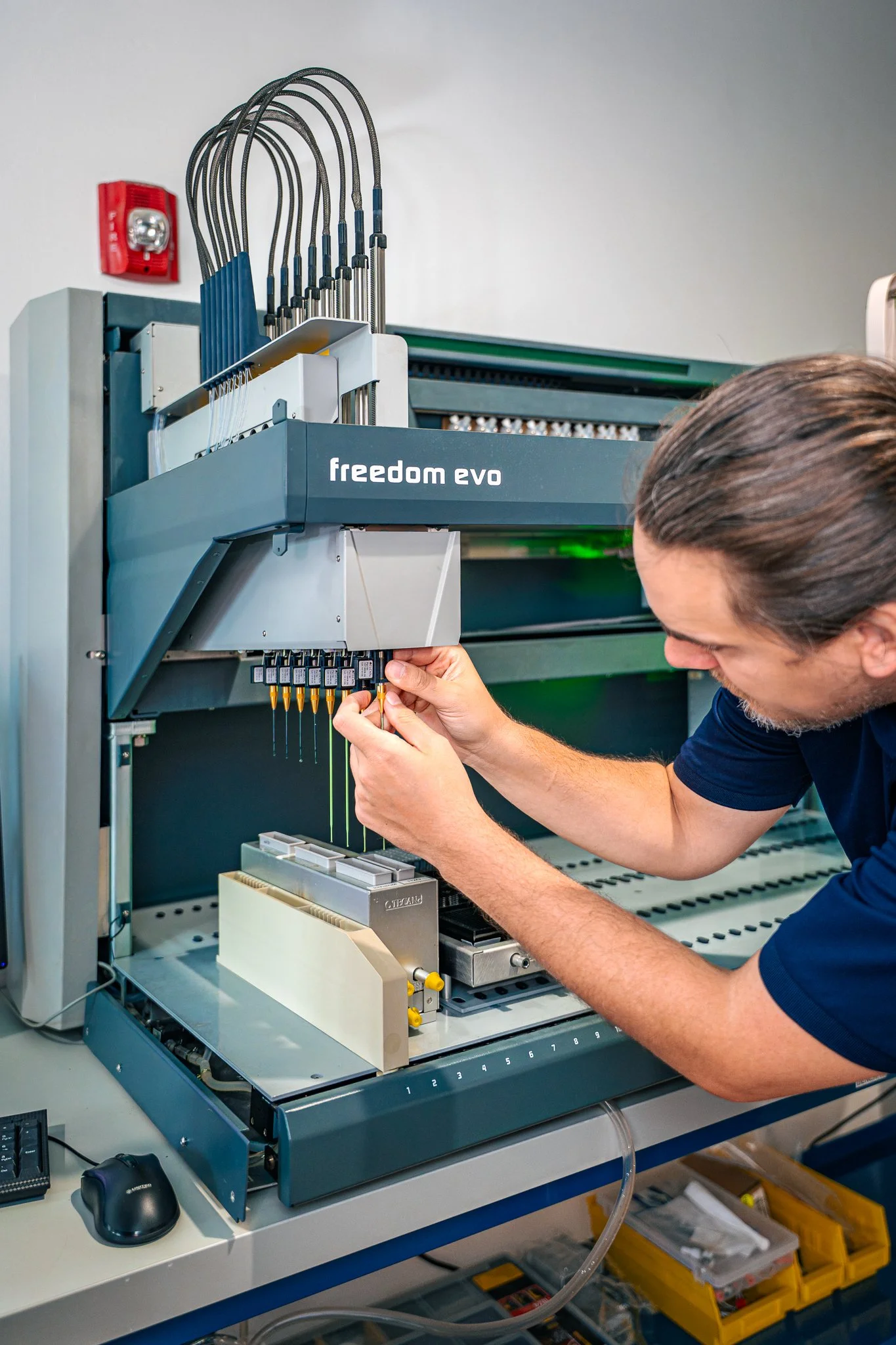 A person working with a large laboratory instrument labeled 'freedom evo' in a laboratory setting.