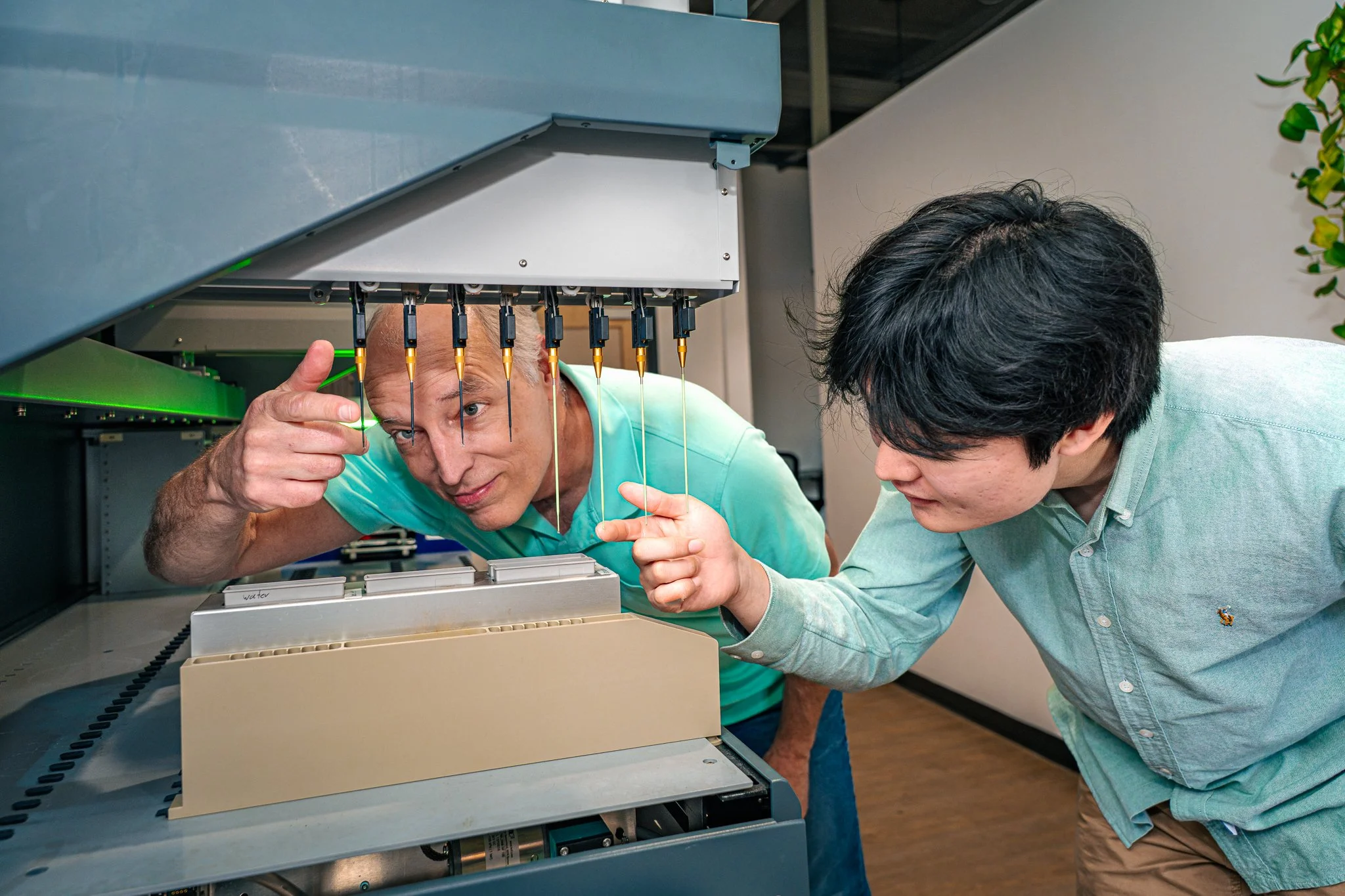 Two men inspecting a scientific instrument with probes inside a laboratory.
