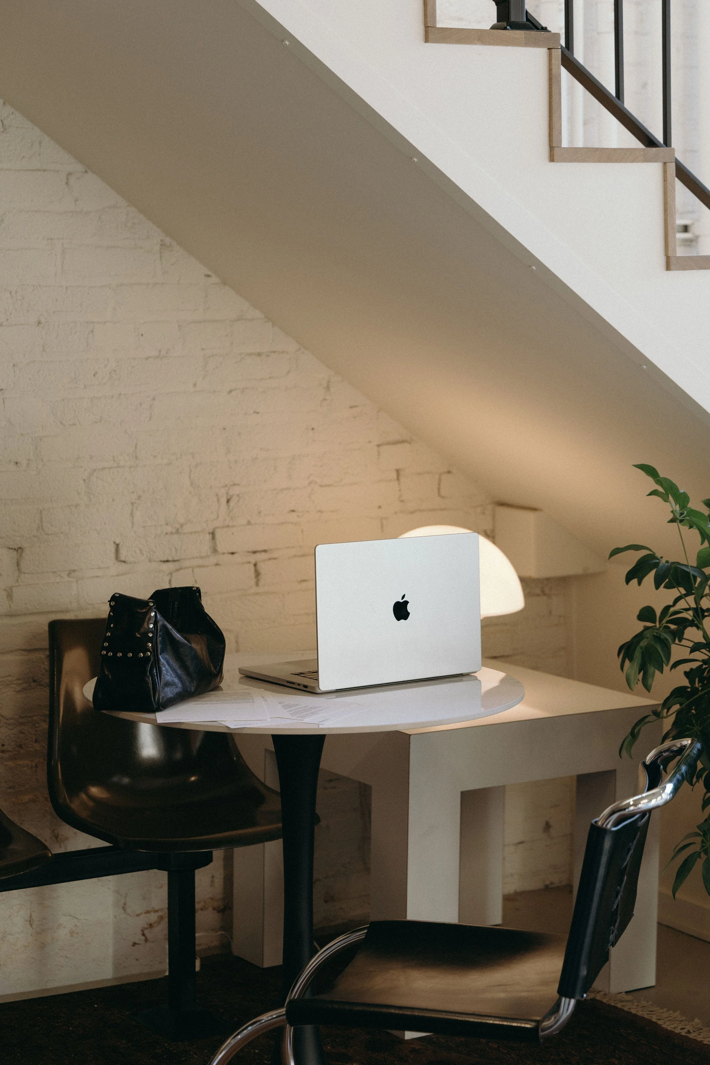 Computer on table with black leather chairs.