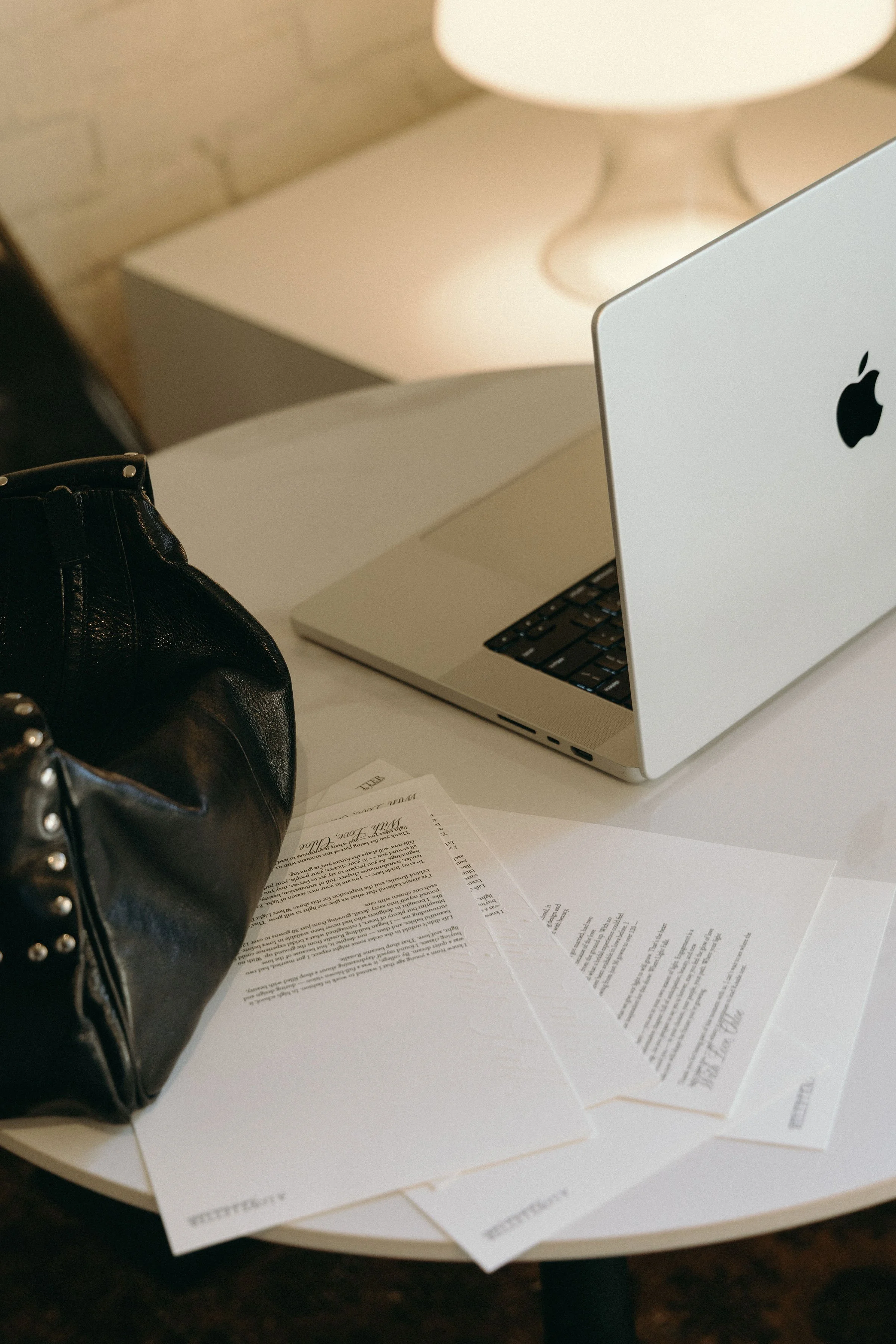Computer on table with printed papers around it.