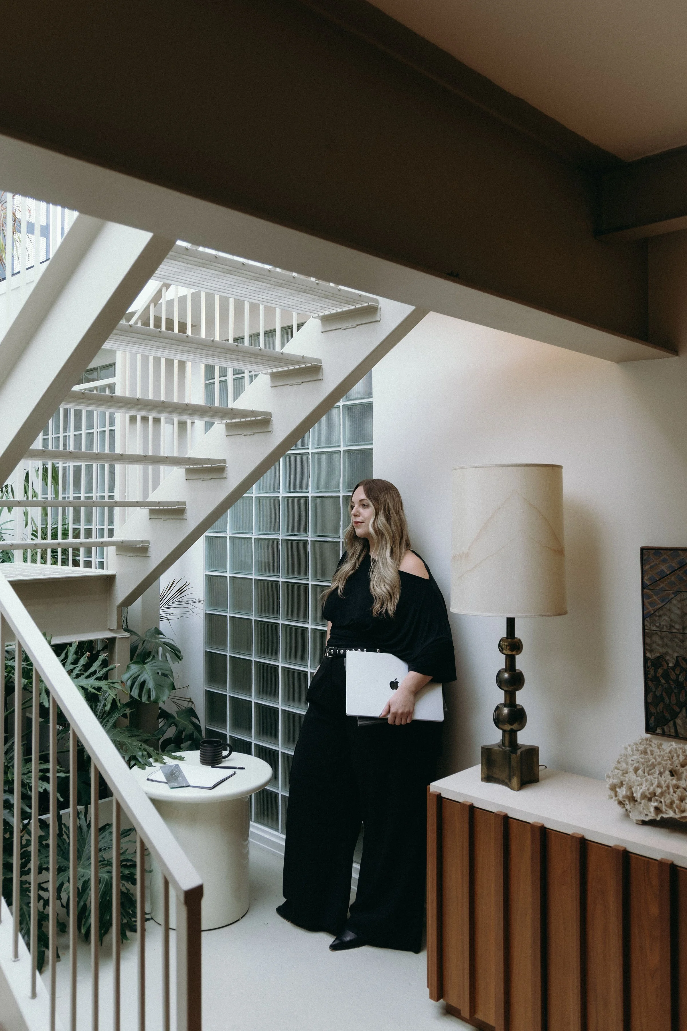 Woman standing near glass block wall with a computer in her hand.
