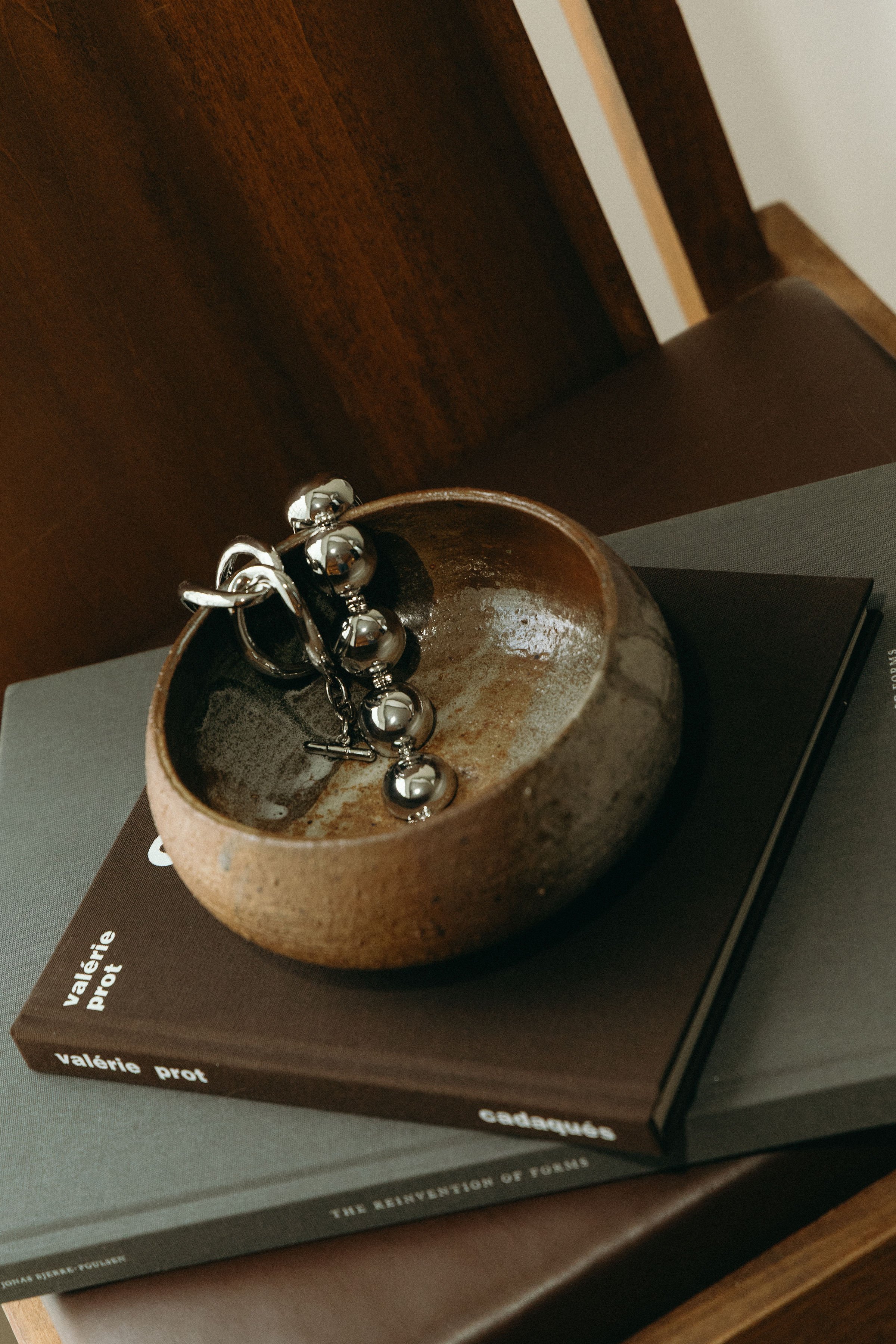 Ceramic bowl and book on lounge chair.