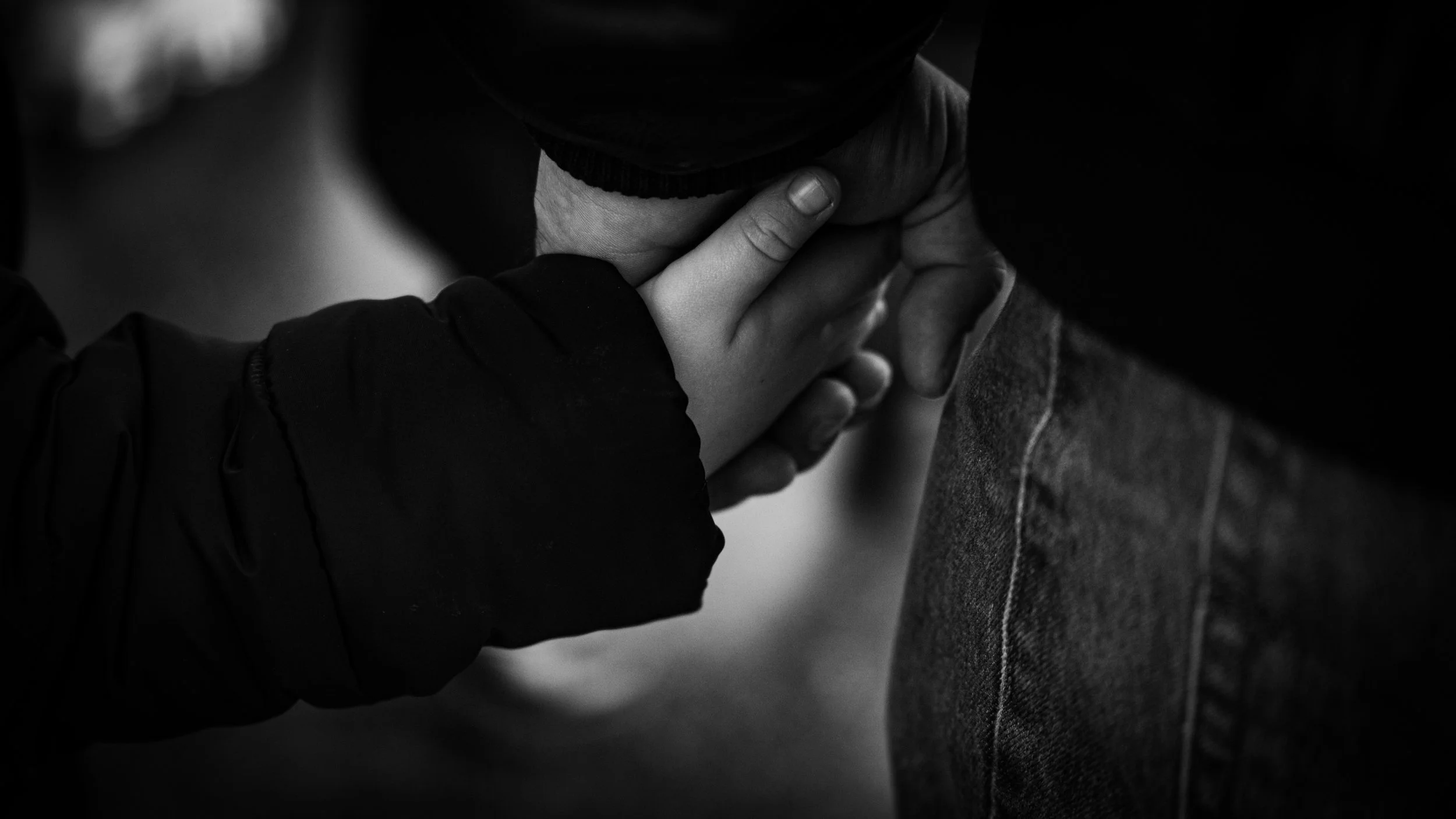 Two people holding hands, one person’s hand on top of the other’s, in black and white.