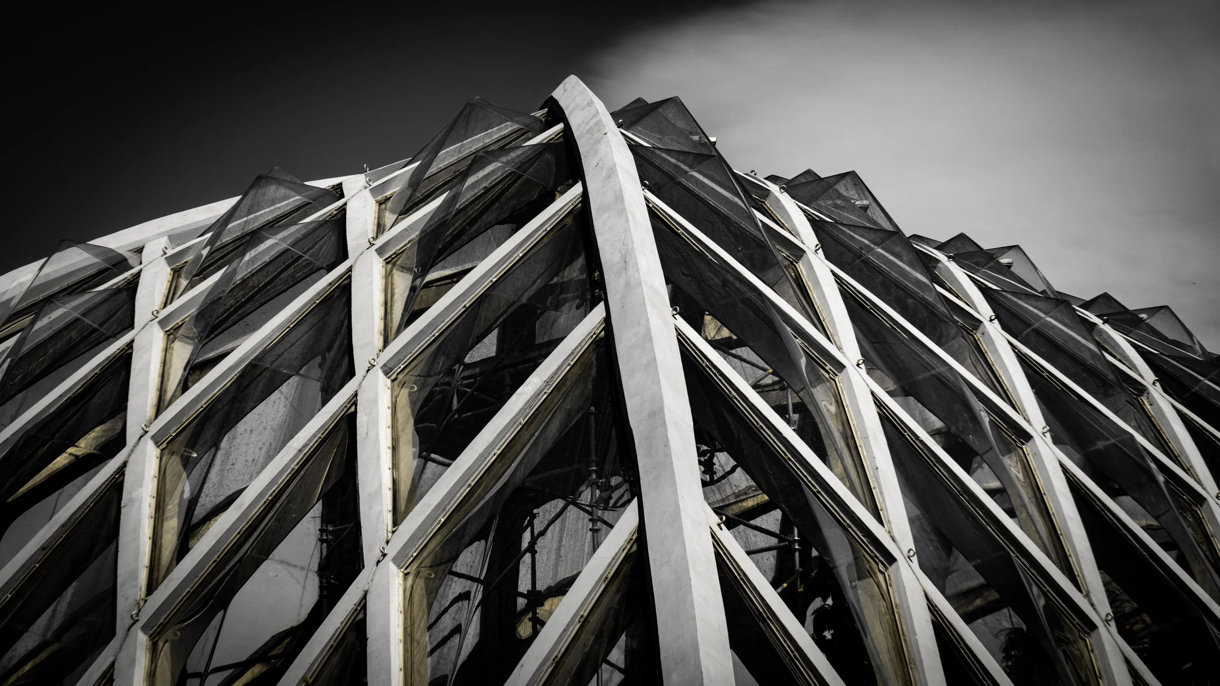 Close-up view of modern building with glass and metal facade, black and white photo, angular architecture.