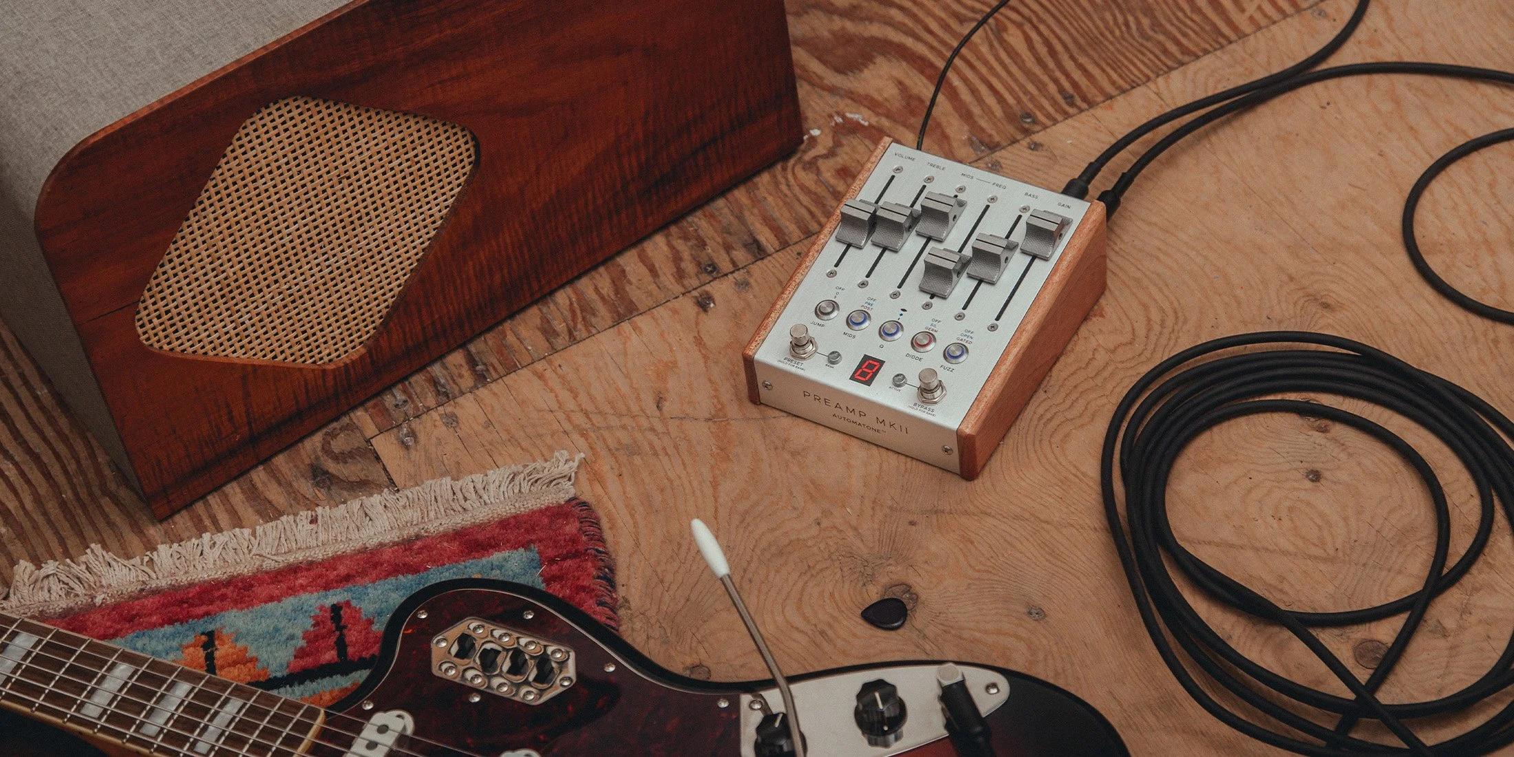Preamp MKII pedal on the floor next to a guitar.