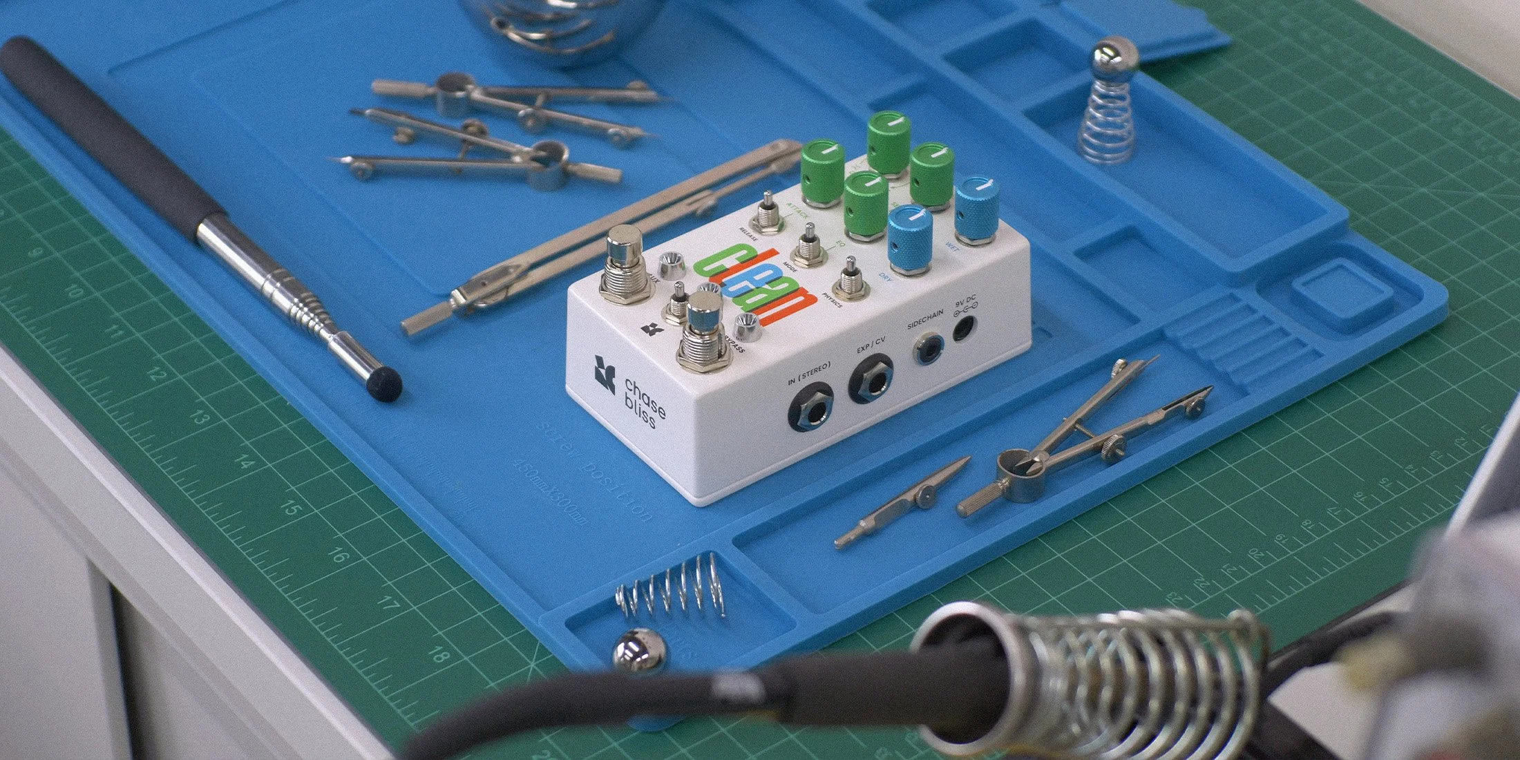 Clean effects pedal from Chase Bliss on a blue tray with scientific tools around it.