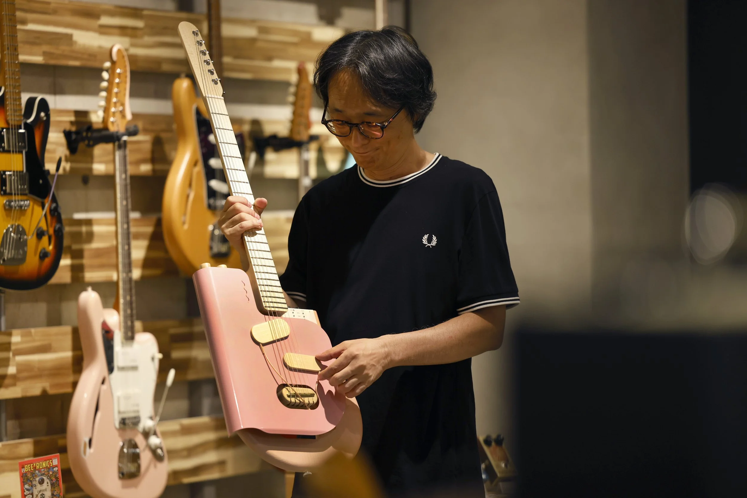 Take from Umbrella holding a pink Verso guitar.
