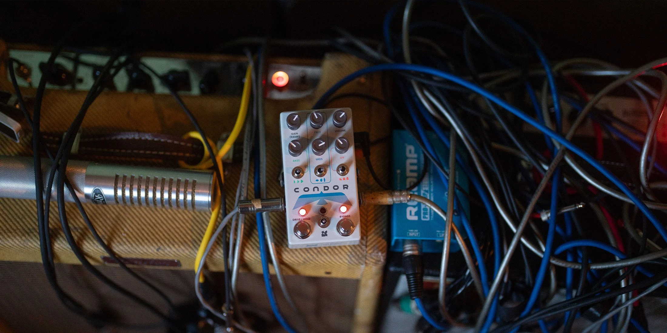 Messy guitar cables with the Condor HiFi effects pedal from Chase Bliss on top of a guitar amplifier.
