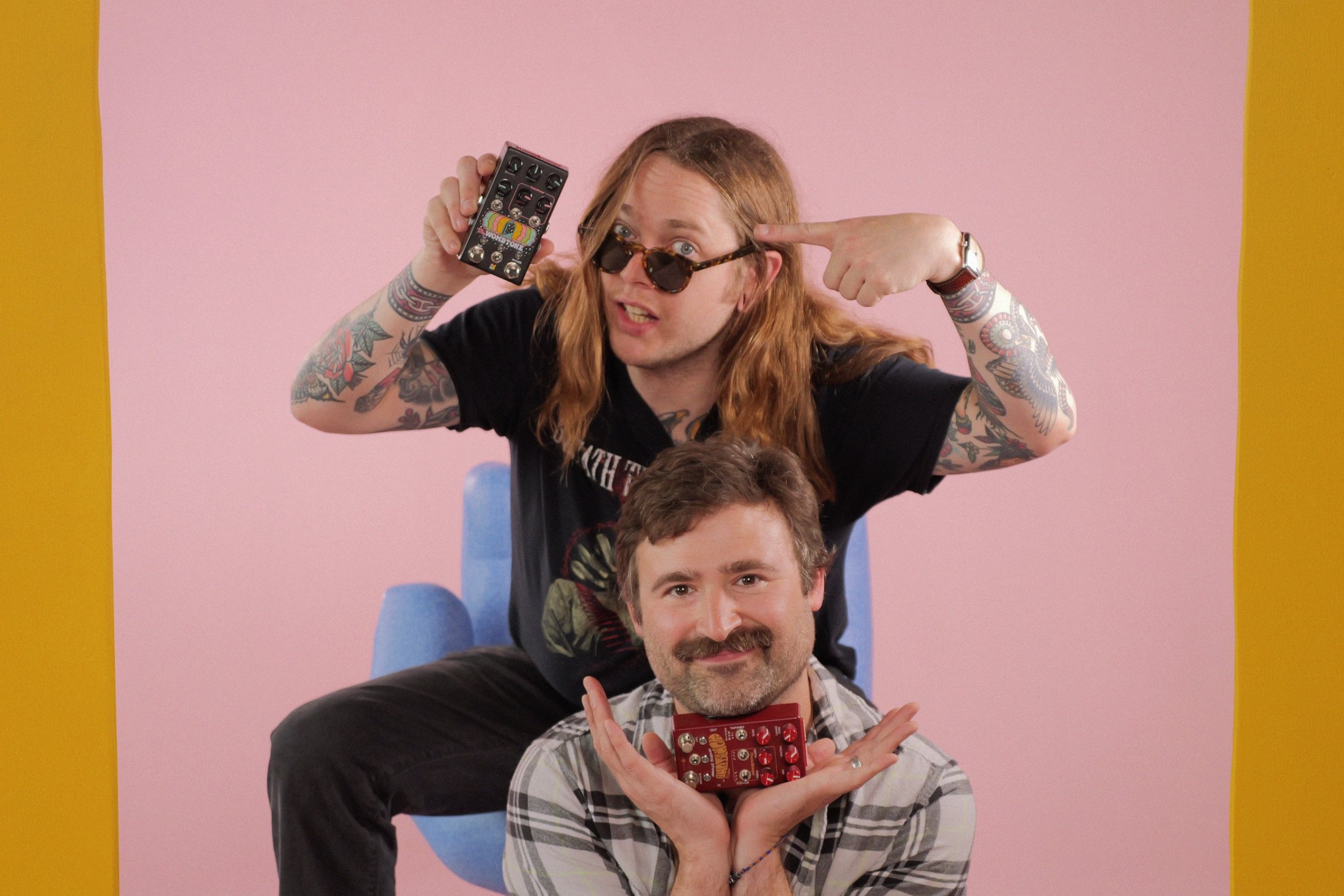 People (Joel Korte and Billy Strings) smiling and holding up the Billy Strings signature Wombtone effects pedal by Chase Bliss.