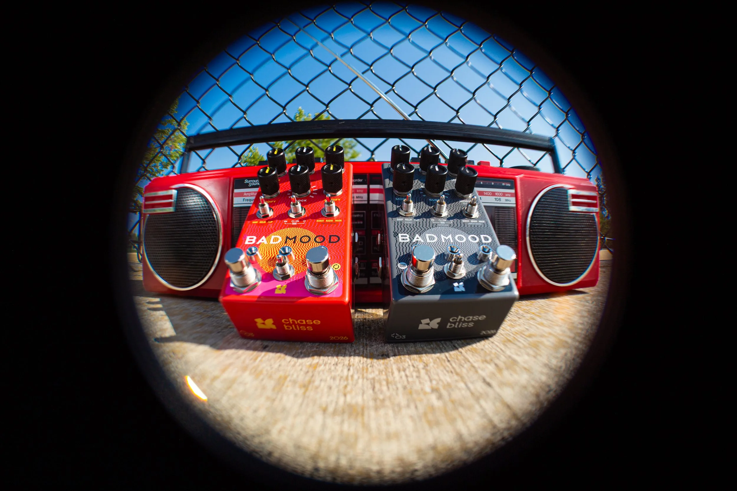 Grey and Red "BAD MOOD" effects pedals by Chase Bliss leaning against a retro boombox.