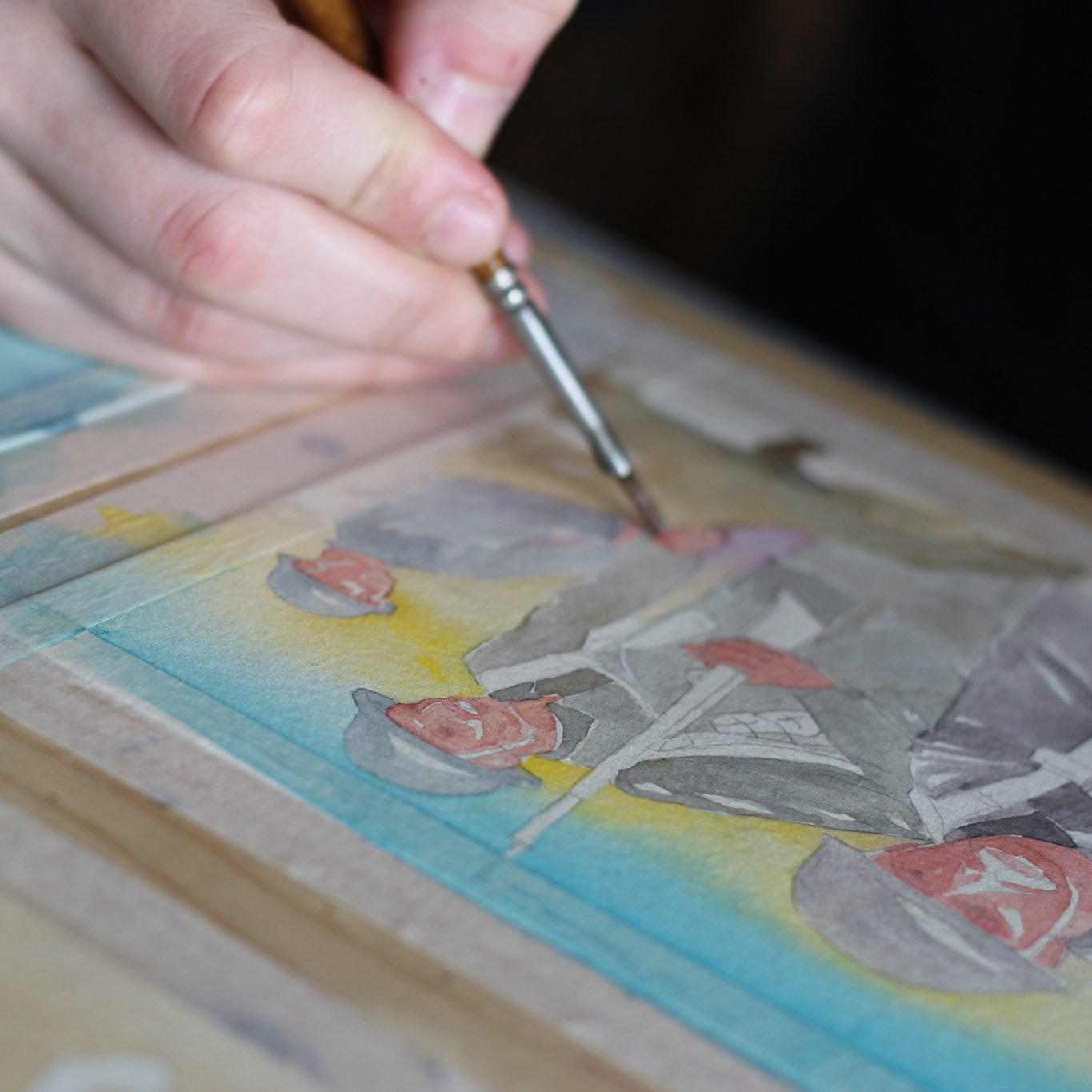 A person painting a watercolor picture of a still life with roses and a landscape in the background.