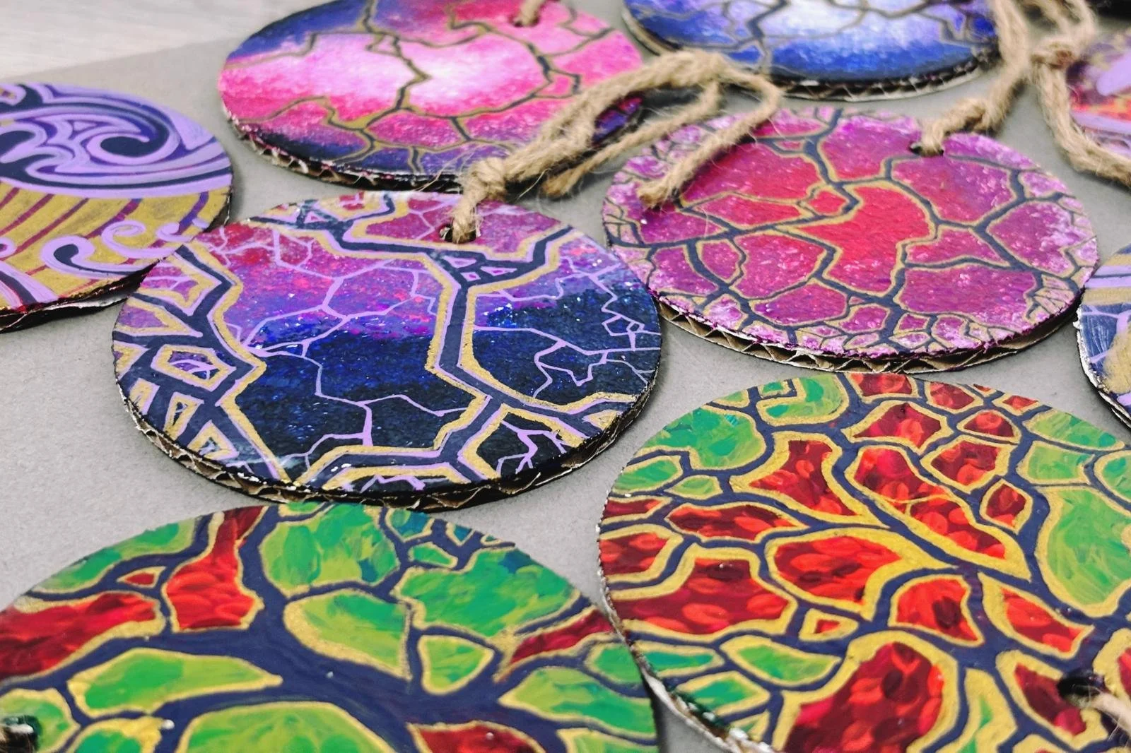 Ornamente circulare pictate colorate, cu modele complicate și sfoară legată, se sprijină pe o suprafață plană.