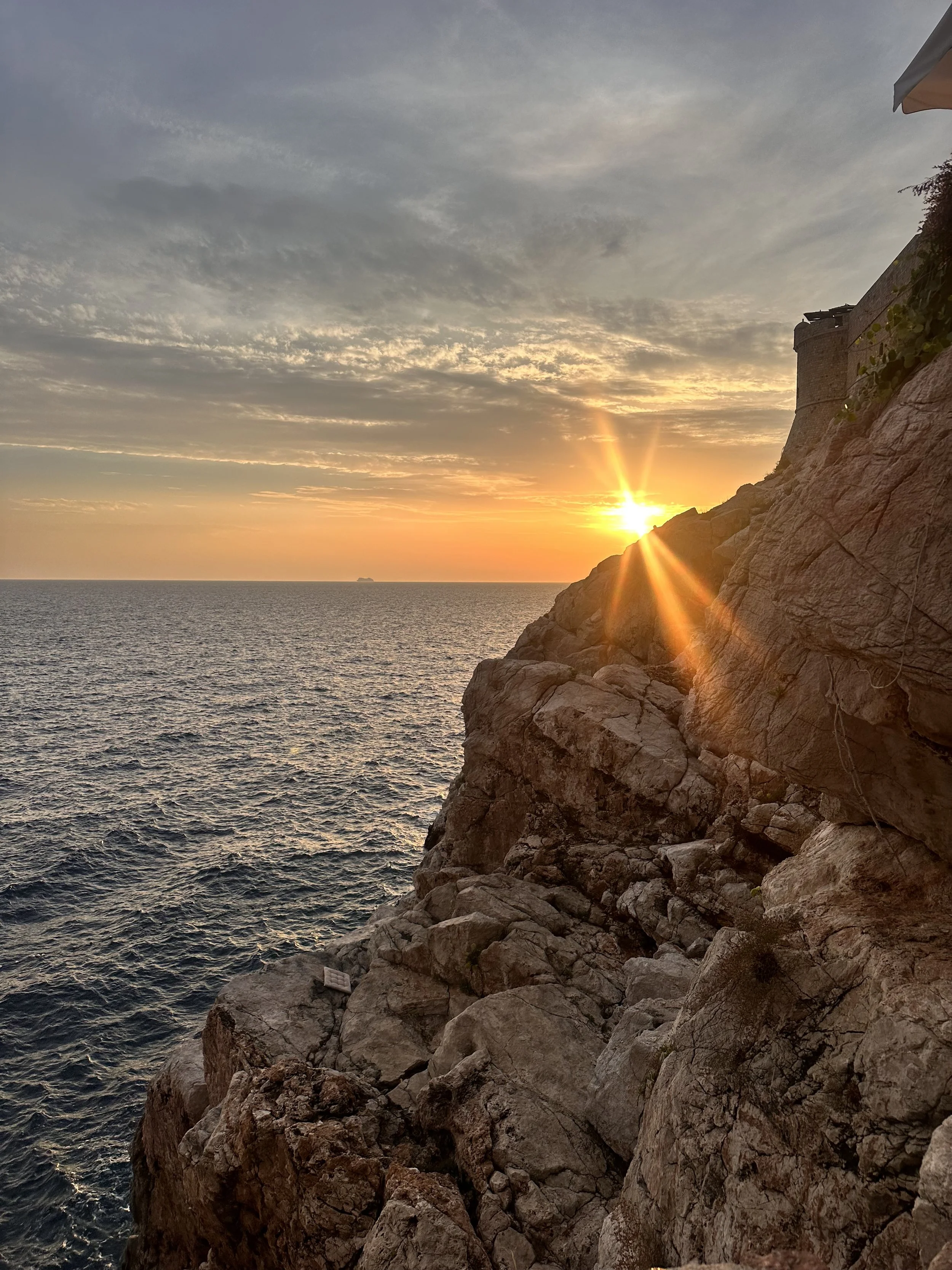 Sunset over ocean behind rocks