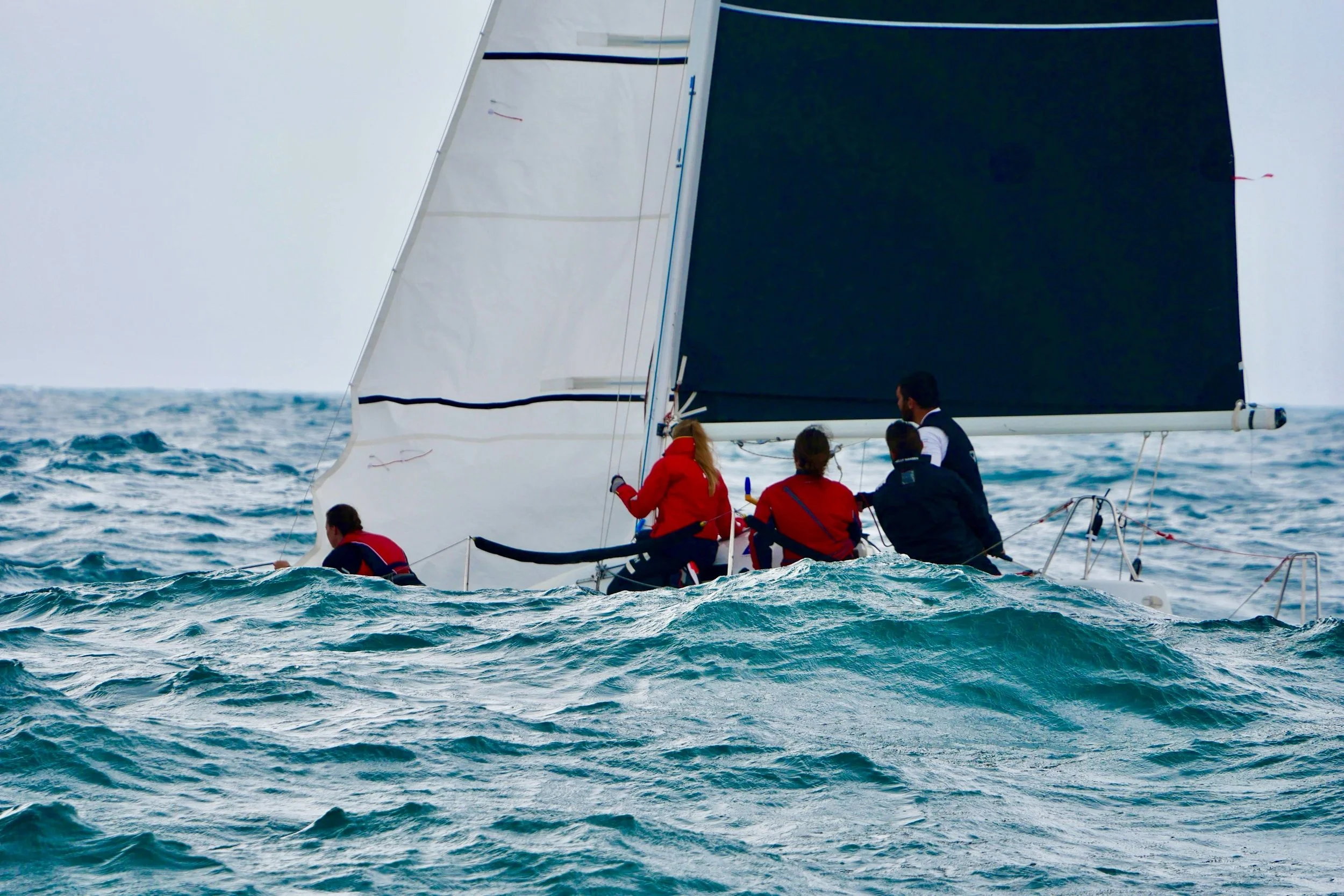 Un gruppo di persone su una barca a vela in mezzo al mare con onde.
