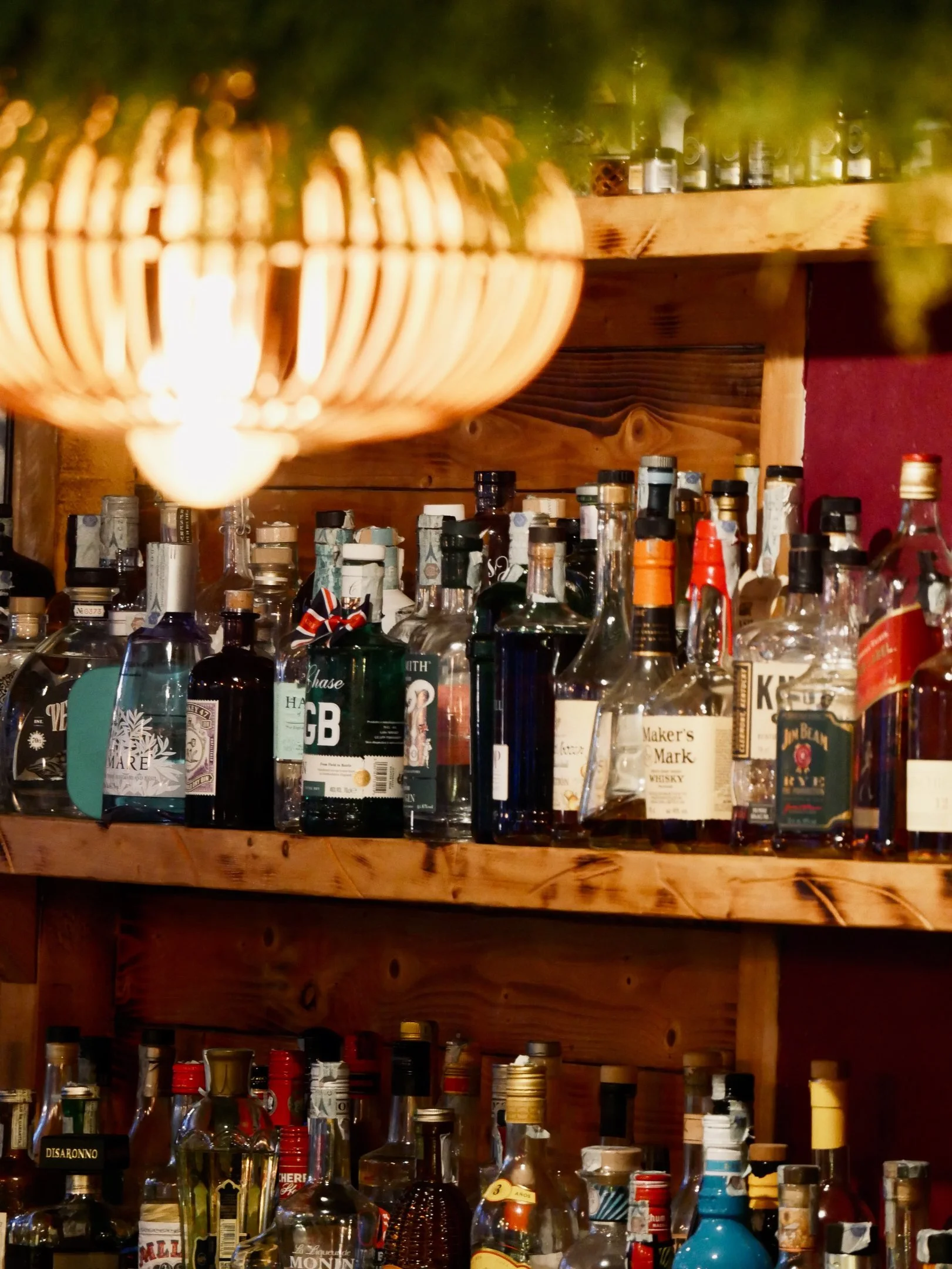 Ripiano di bottiglie di alcolici in un bar, con diversi tipi di liquori e whisky su uno scaffale di legno.