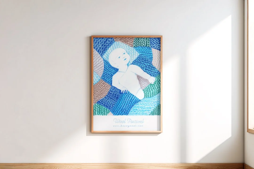 Framed A3 poster for a Wool festival featuring baby wrapped in blue woollen blanket. 