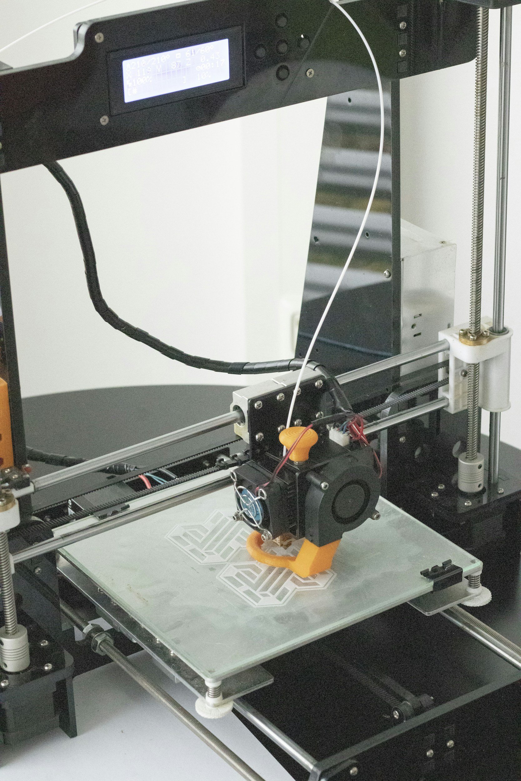 A 3D printer extruding filament onto a print bed with a partially finished geometric design.