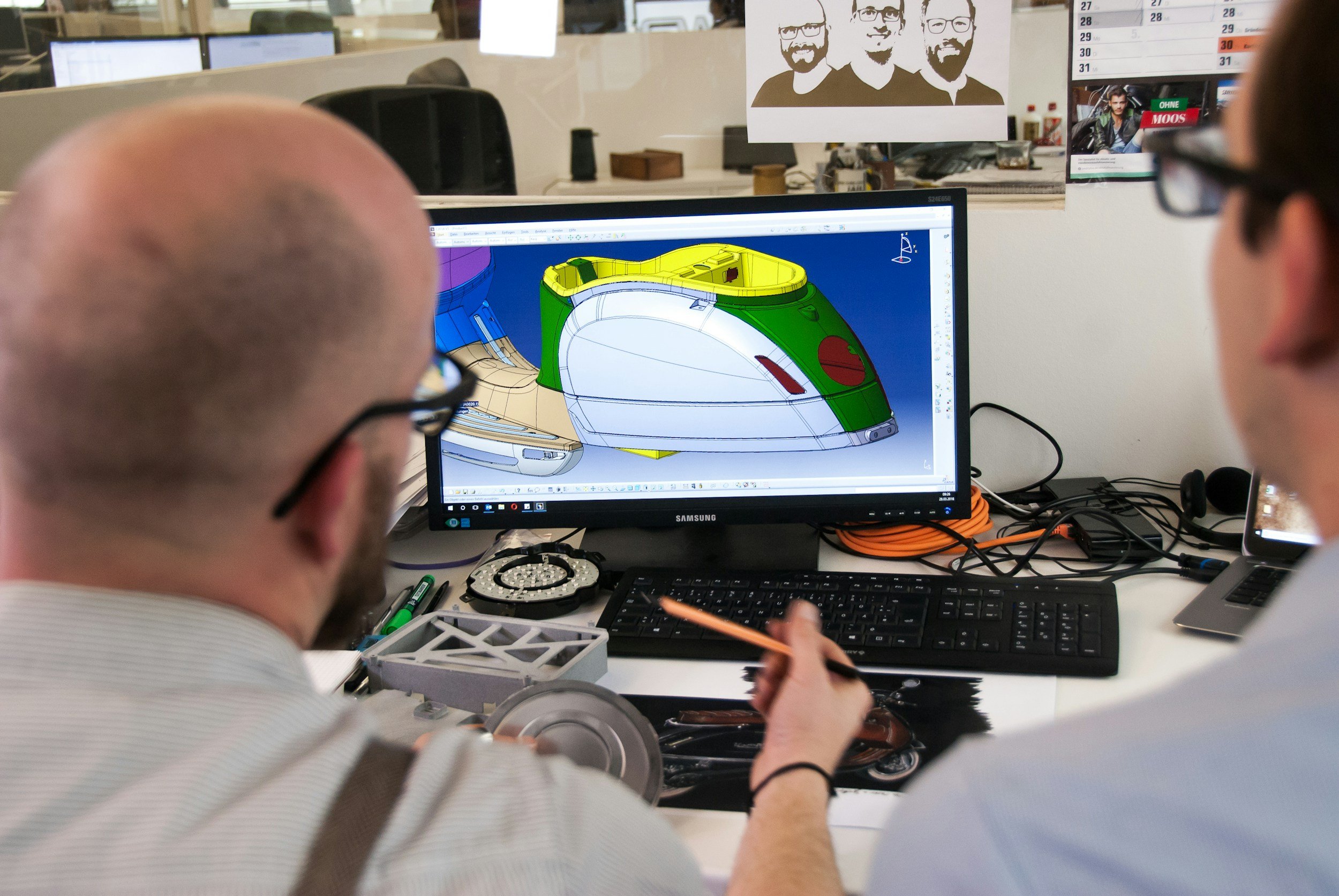 Two people working on a computer with 3D modeling software showing a colorful car design.
