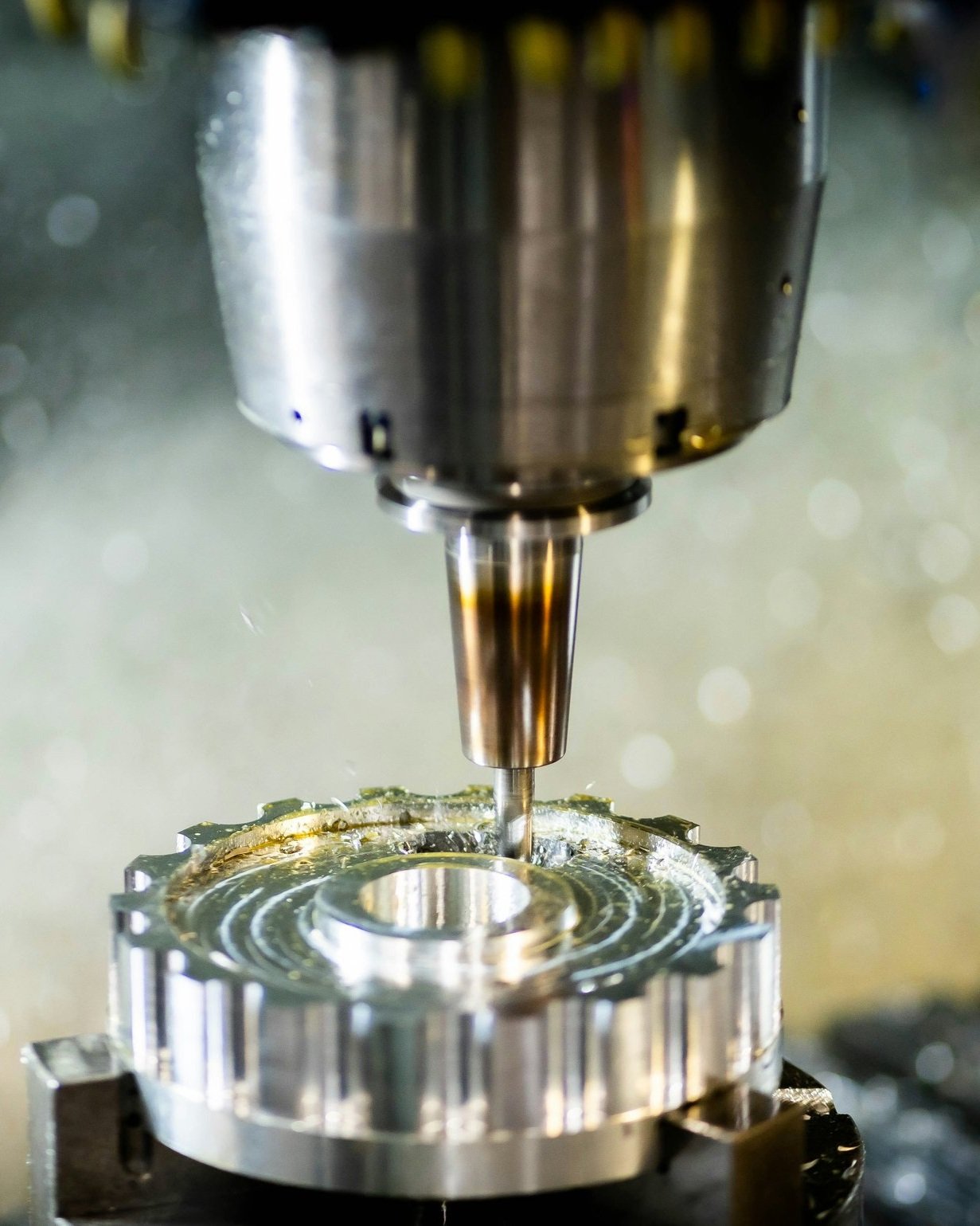 Close-up of a metal CNC machine milling a circular metal component.