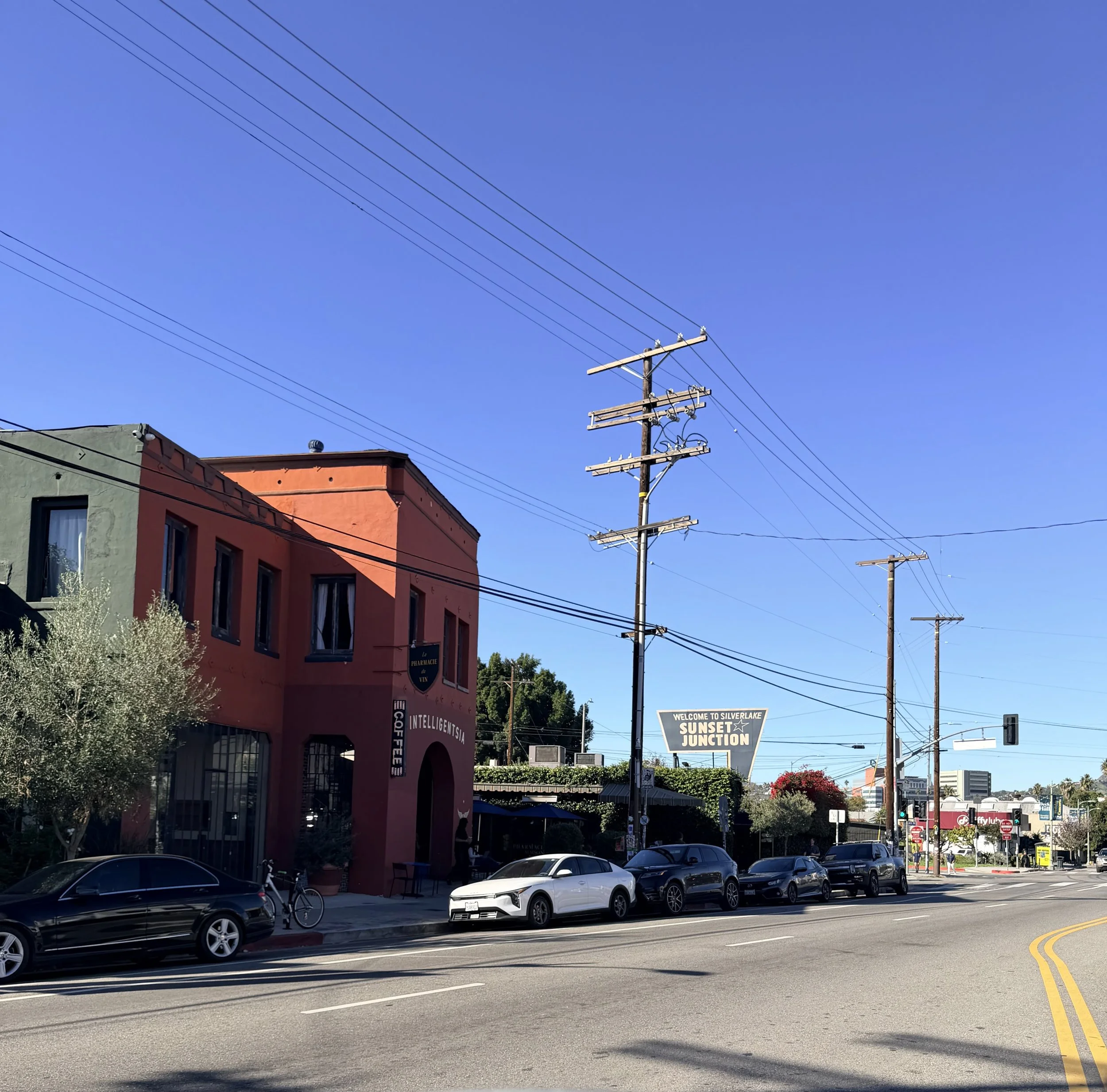 Street scene in Silverlake with colorful buildings, parked cars, and utility poles under a blue sky.