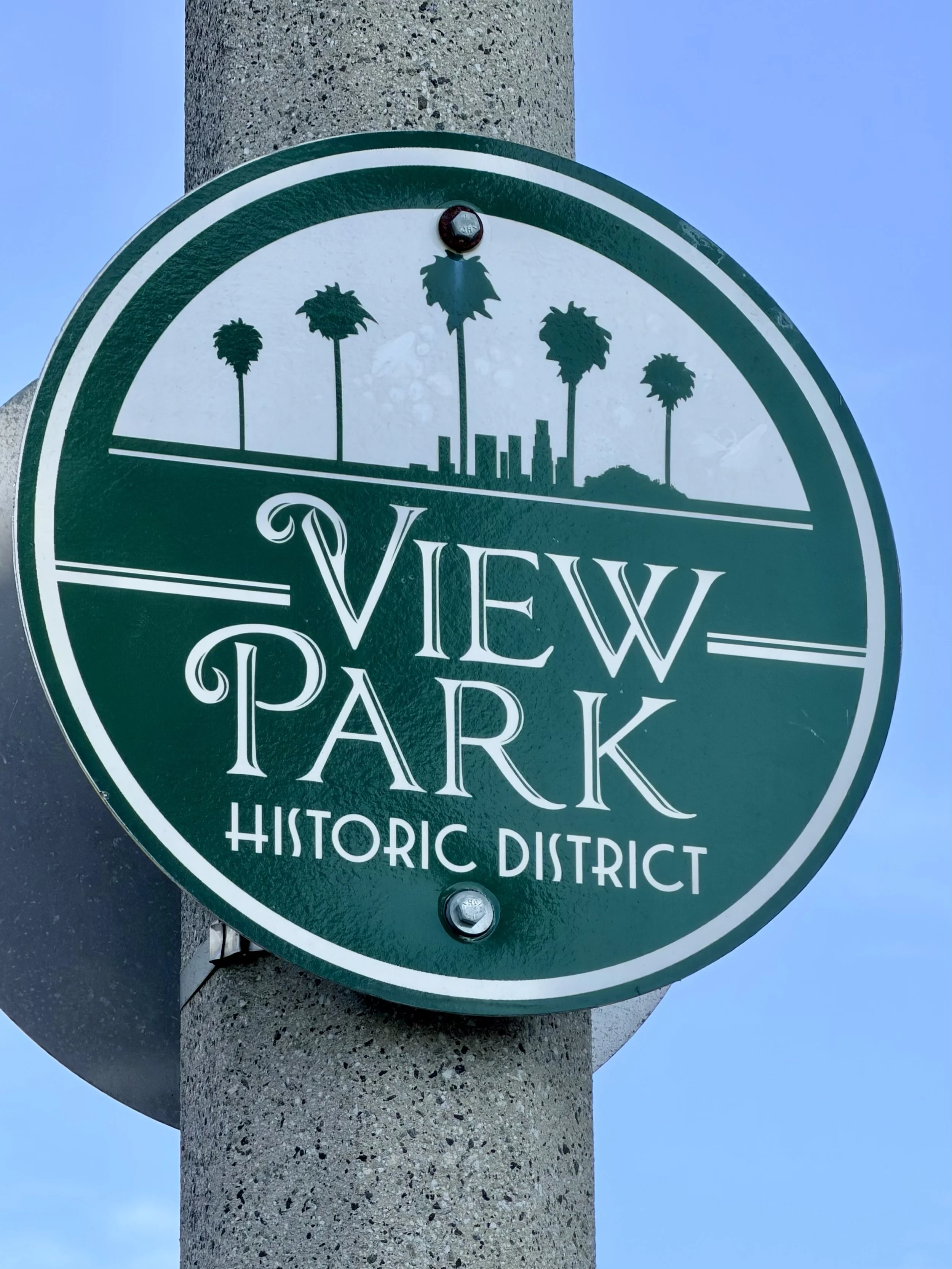 View Park Historic District sign with palm trees and a city skyline silhouette in the background