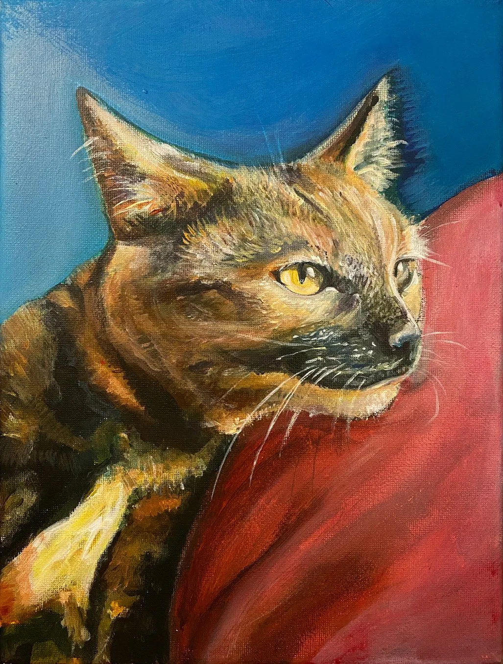 A colorful painting of a tabby cat lying on a red surface, with a blue background visible behind it.