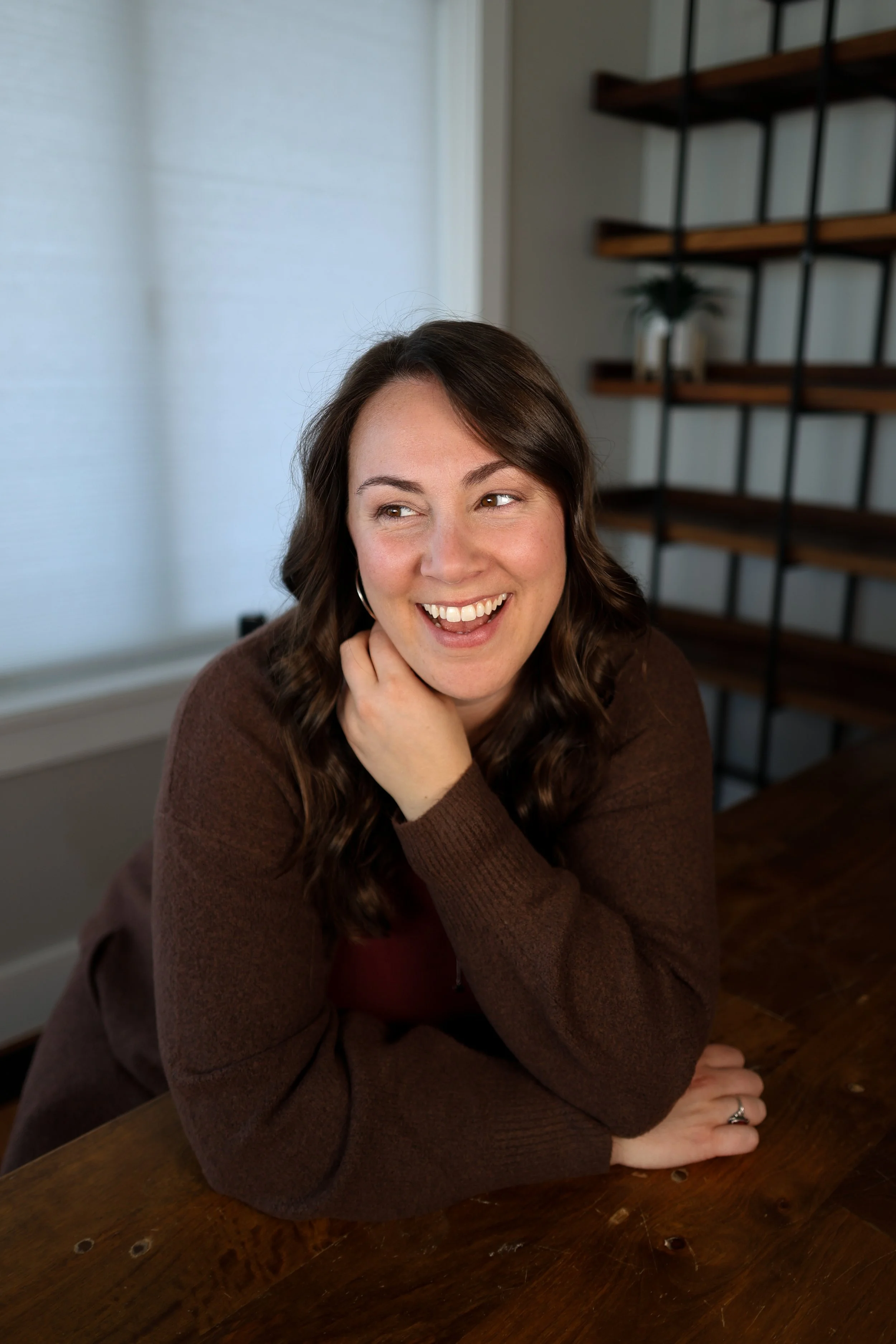 A headshot of Heather from The Nurtured Nest where she is at a table and laughing