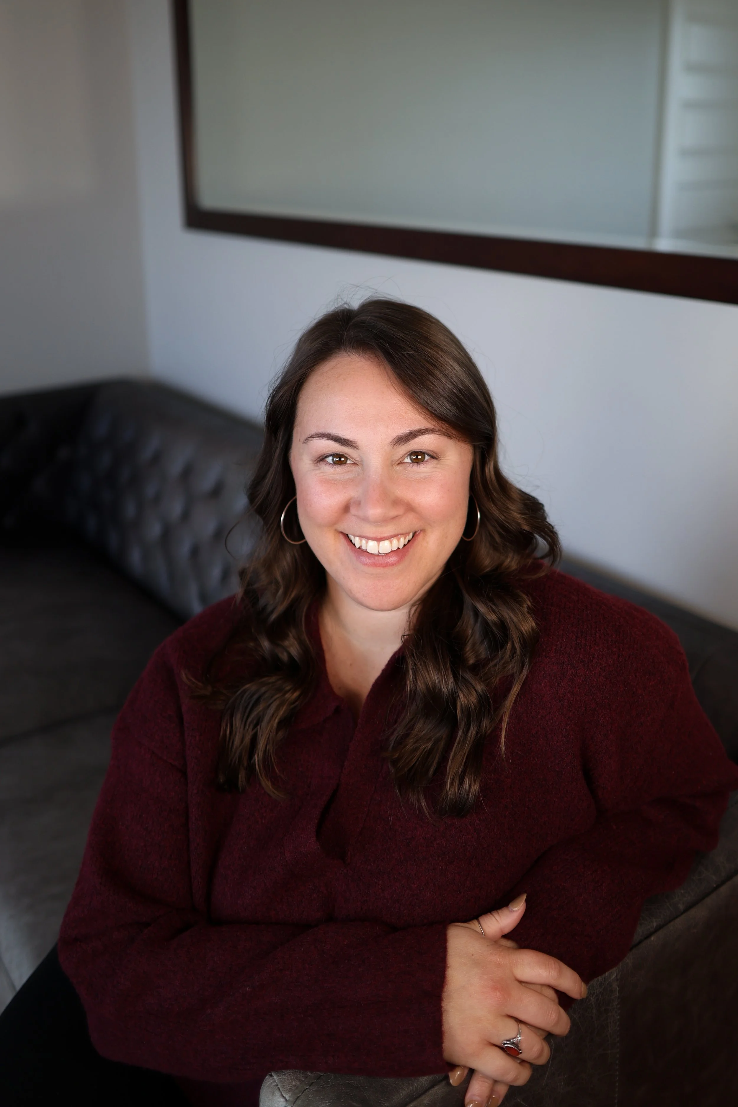 A headshot of Heather from the Nurtured Nest sitting on a couch