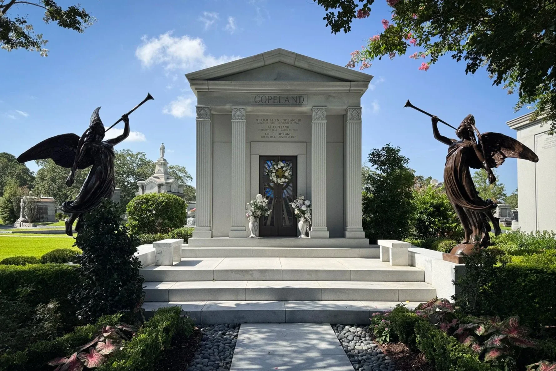 Al Copeland family tomb flanked by two bronze angels blowing trumpets at Metairie Cemetery in New Orleans.