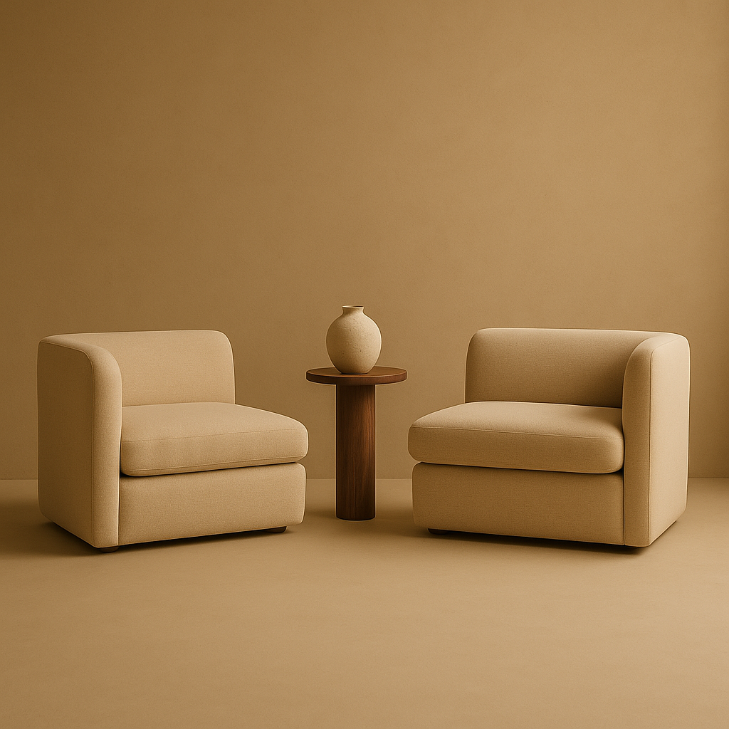 Two beige armchairs with rounded arms and a round wooden side table with a beige vase in between in a minimalist setting.