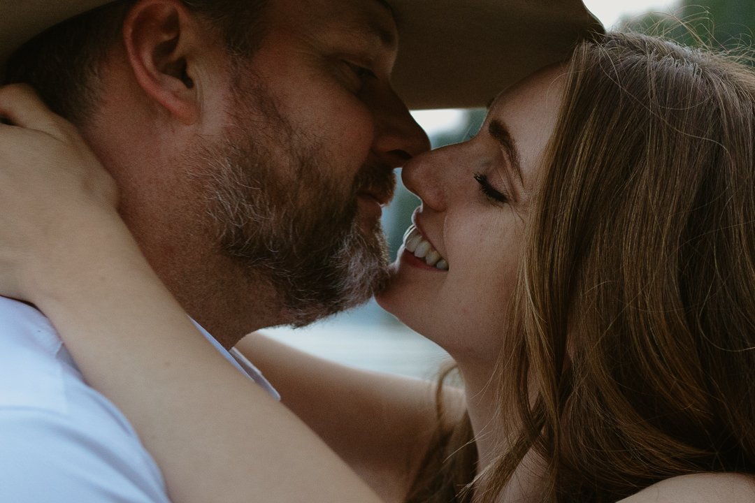 A man and woman embracing closely, leaning in with their foreheads touching, smiling with eyes closed.