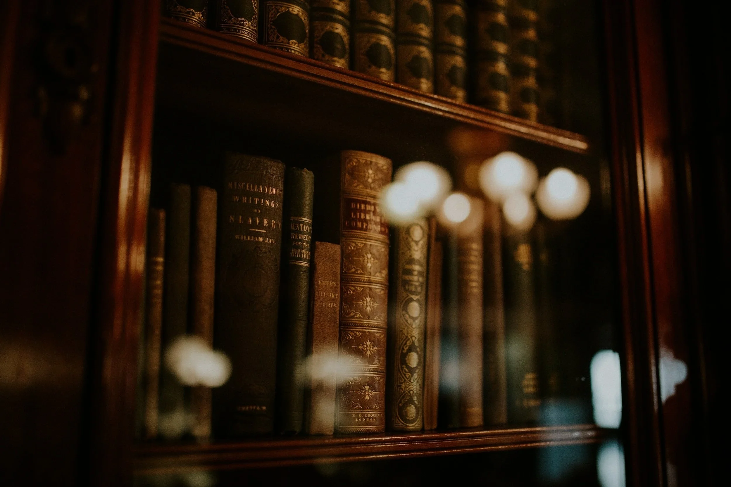 Old antique books on a wooden bookshelf.