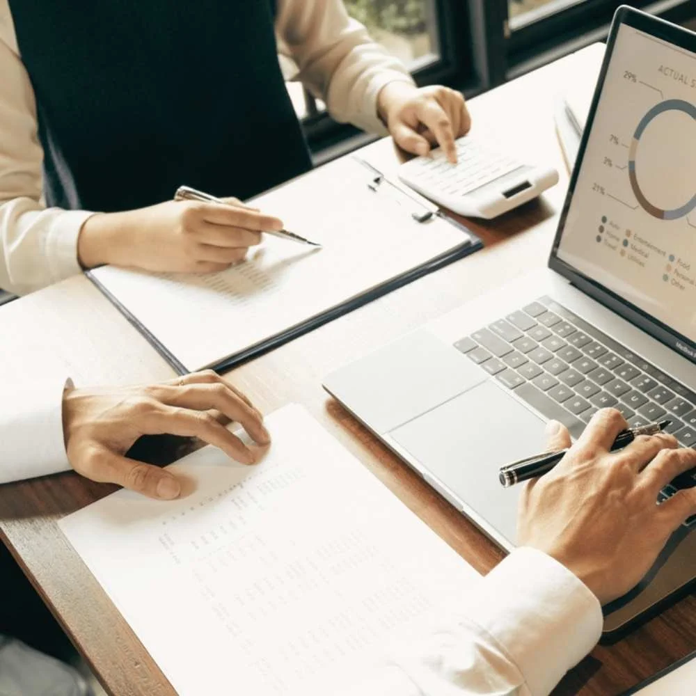 hands at a table with note pads and computer as if at a meeting