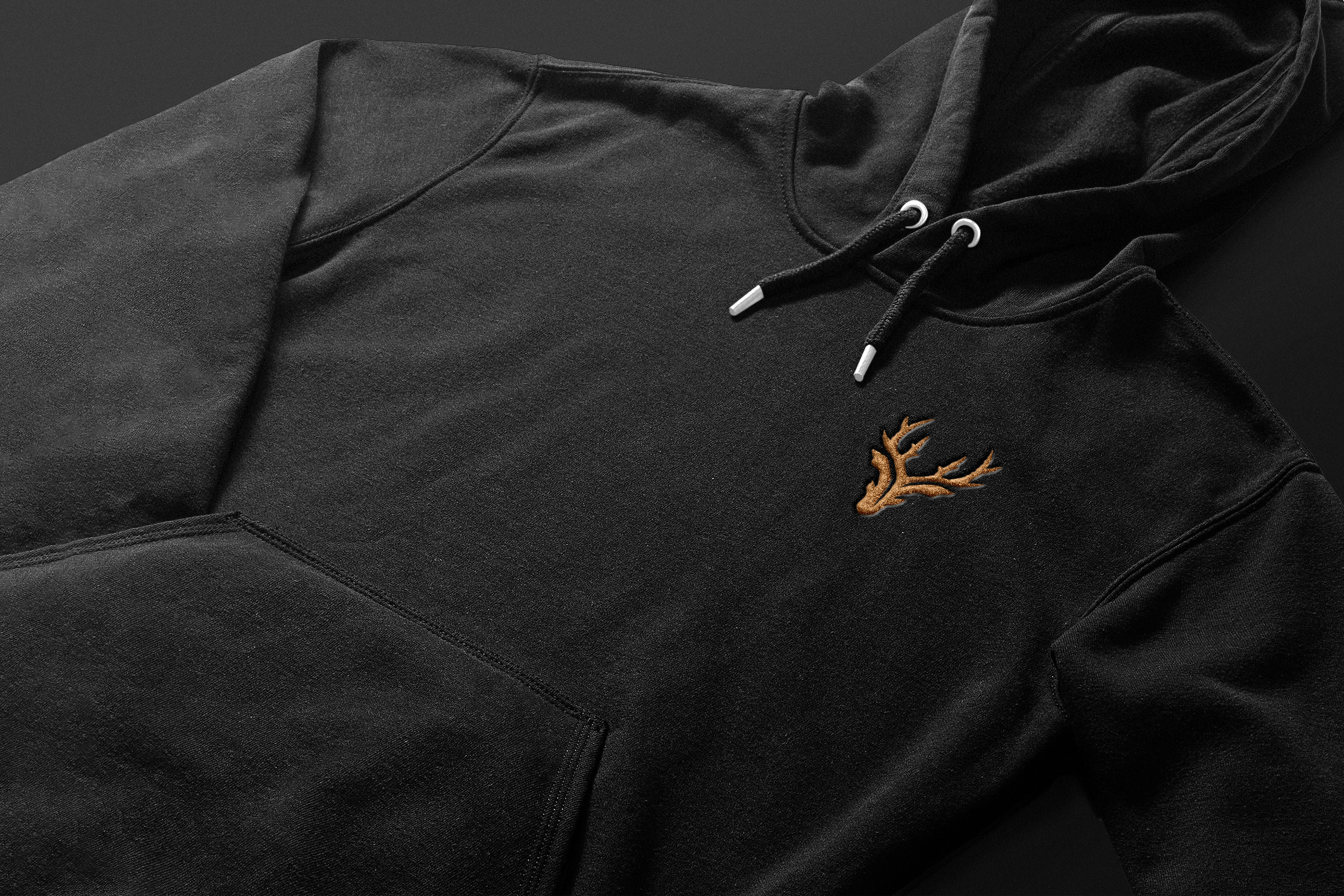 Black hoodie with a brown embroidered deer head logo on the left chest
