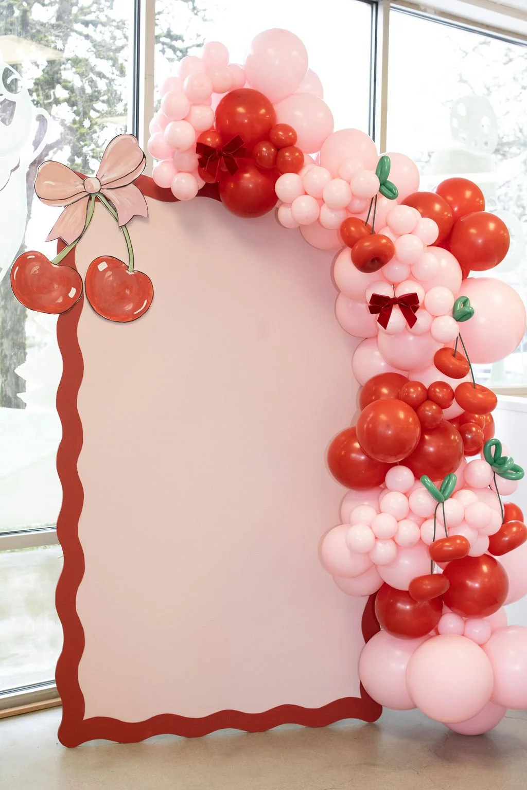 Decorative balloon arrangement with red and pink balloons, cherry and bow illustrations, and a blank white space at the center.
