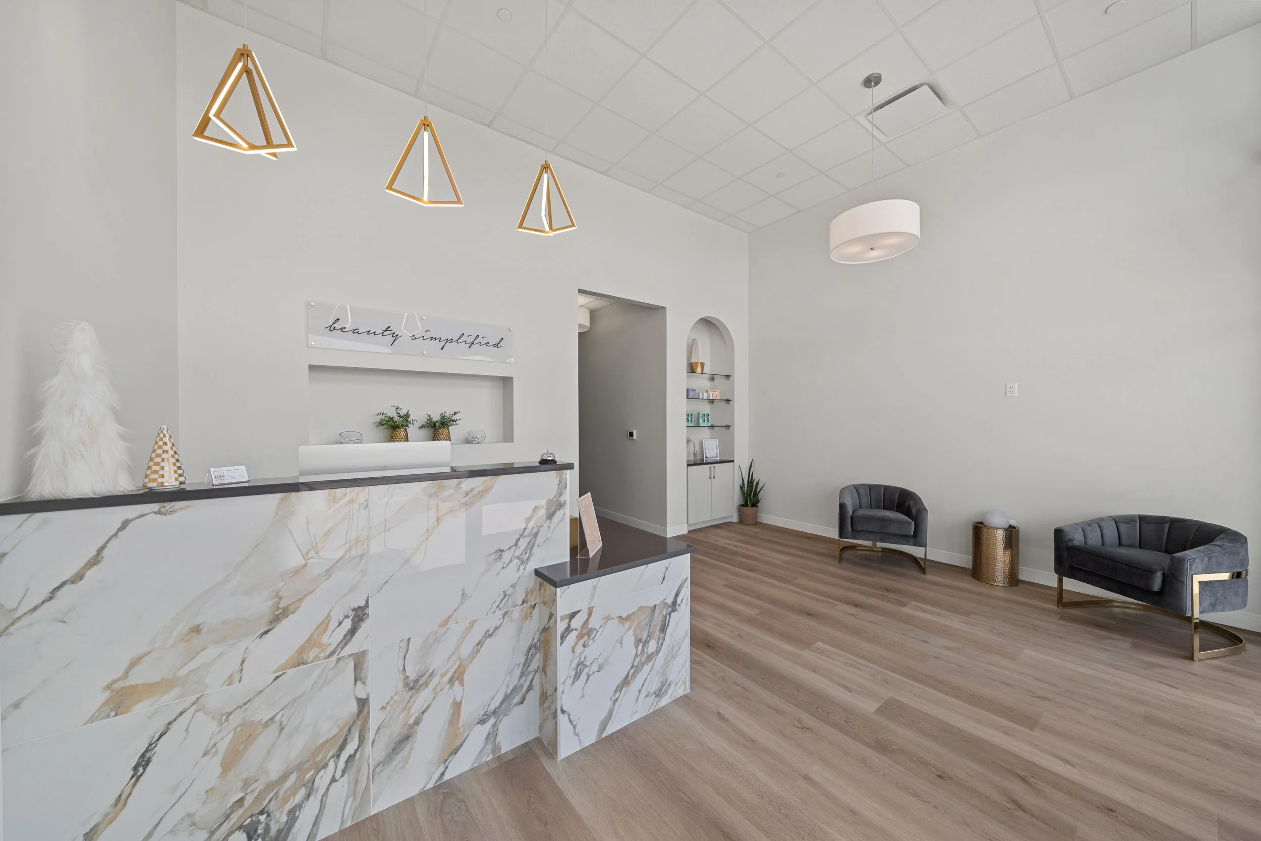 Modern commercial reception area by Romann Construction in Dallas–Fort Worth, featuring marble front desk, gold accents, and custom lighting design.