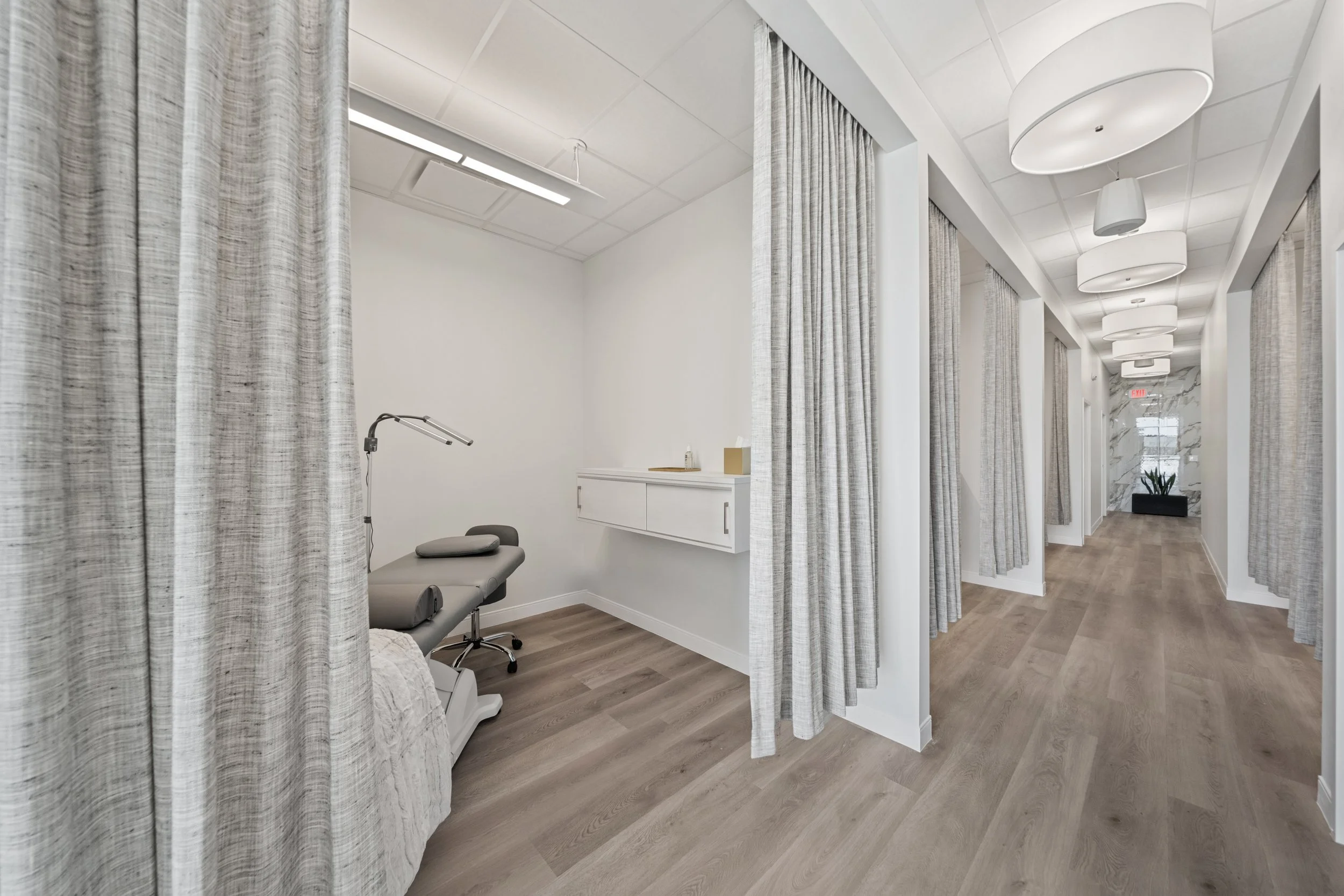 Tenant finish-out project by Romann Construction for a medical office in DFW, featuring exam rooms with custom millwork and privacy curtains.