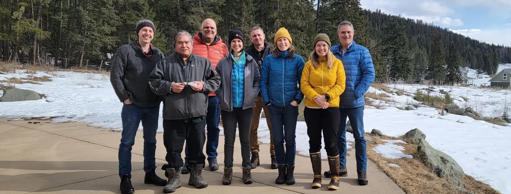 Members of the MWI Advisory Committee standing together in front of a forest with snow on the ground