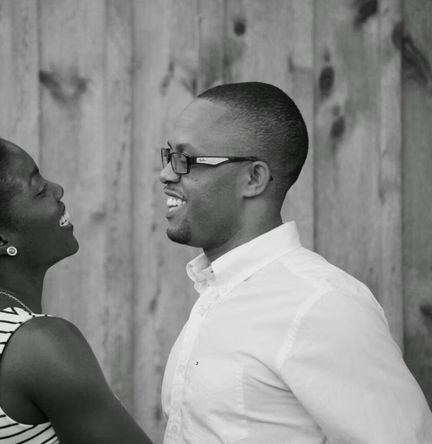 Danielle and Franz Delima of Arise & Own, looking at each other with a wooden wall background.