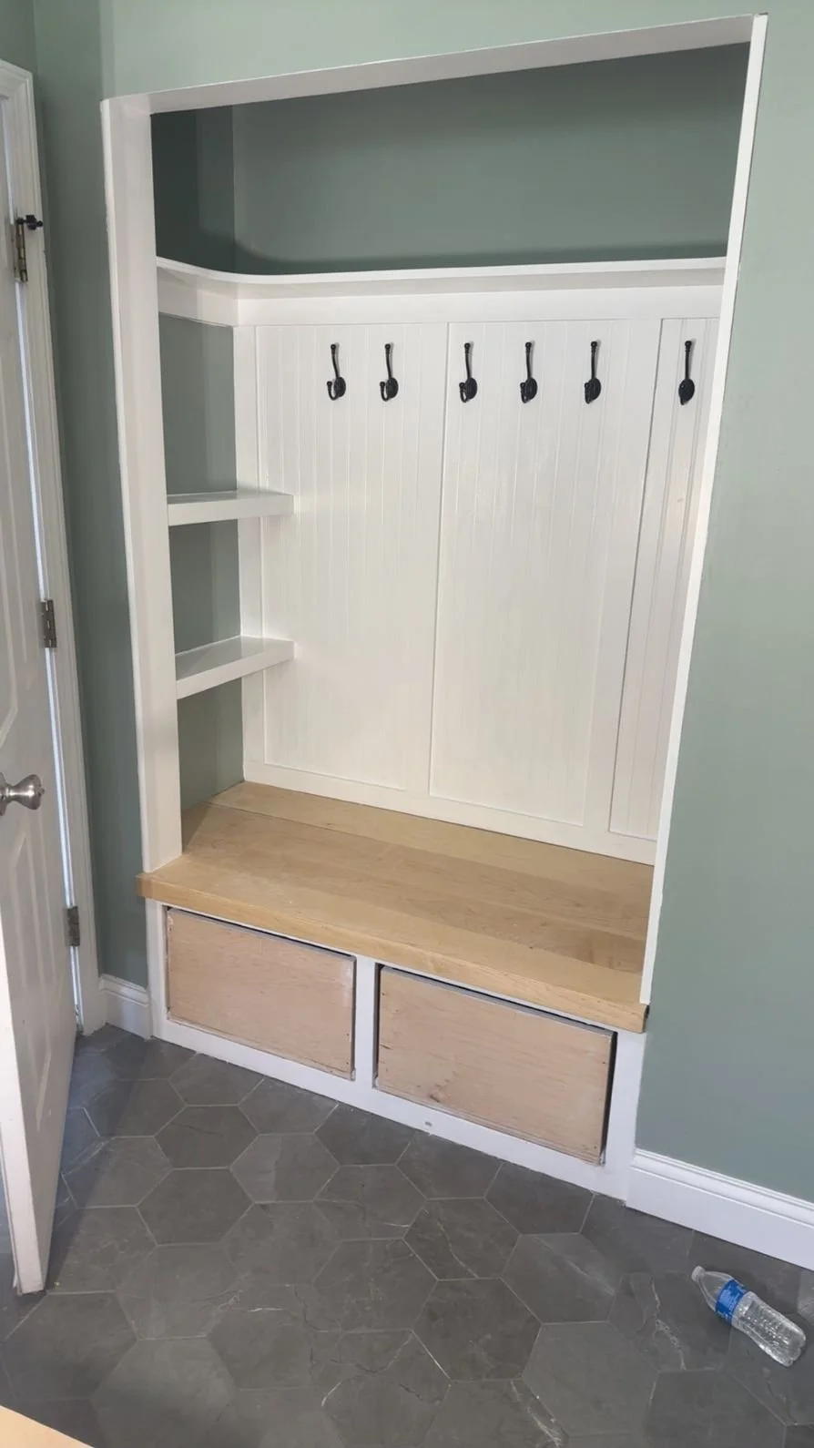 A custom entryway wall with hooks, shelves, and storage drawers, featuring a bench with a wooden top.