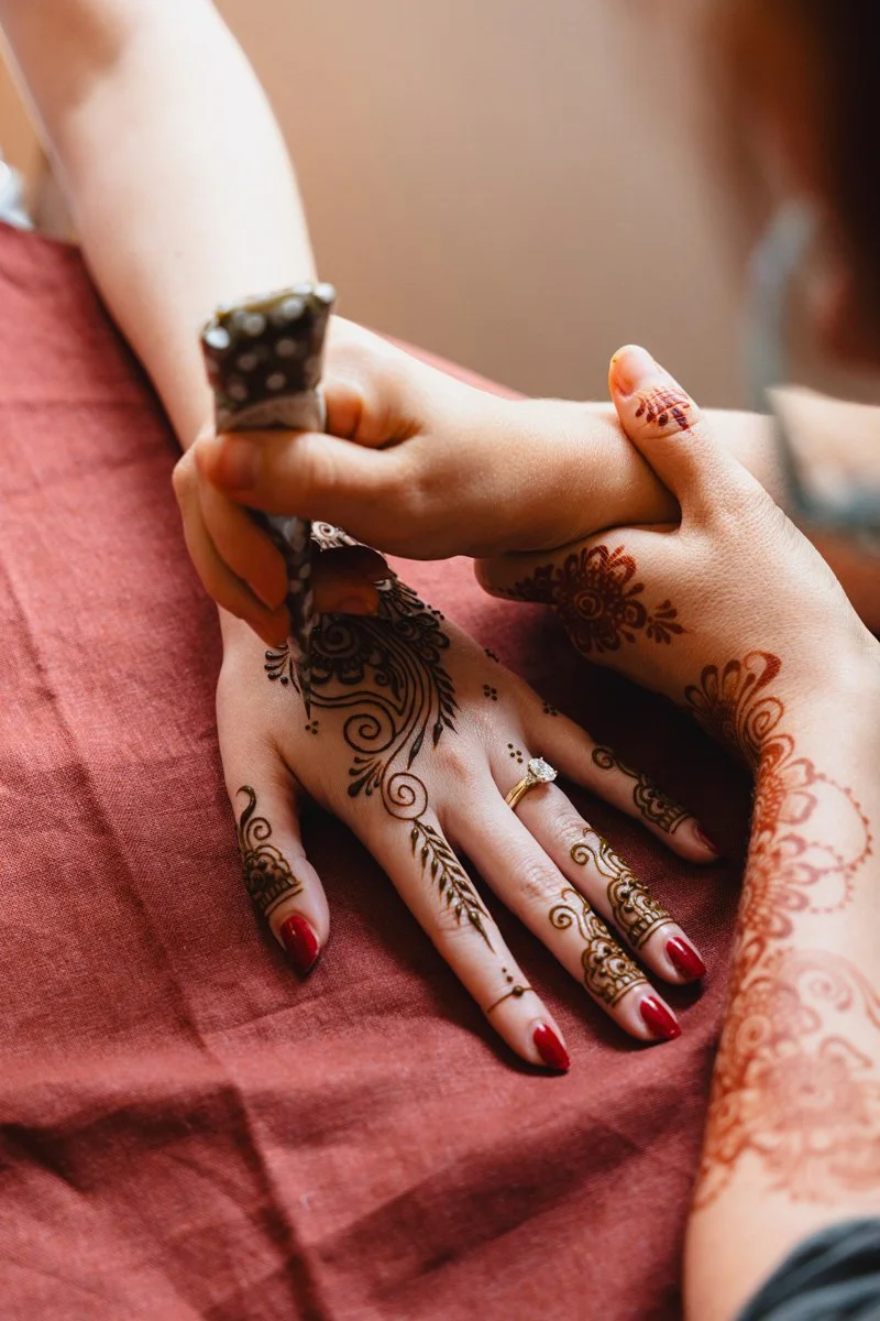 Person applying henna tattoo to another person's hand and fingers.