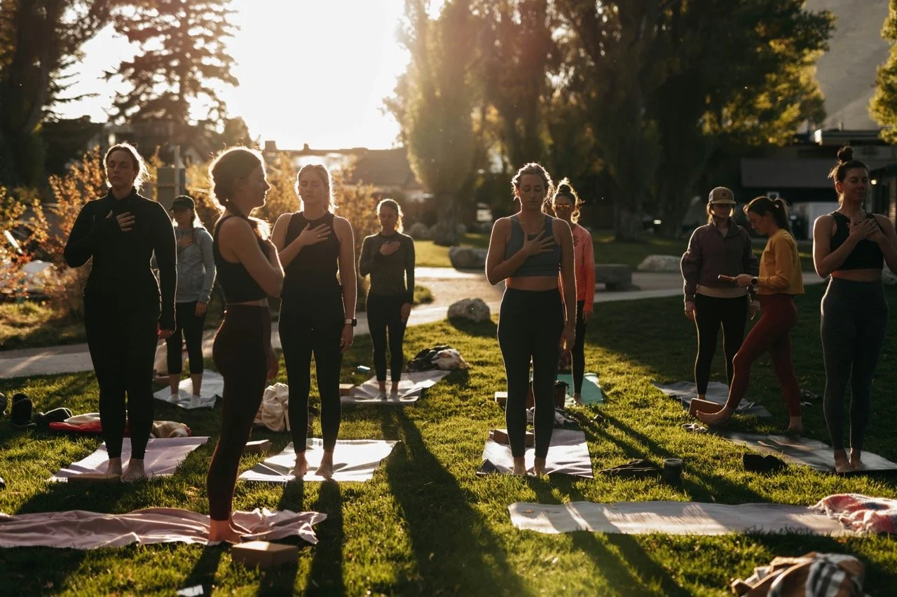 group of women performing yoga outdoors during sunset