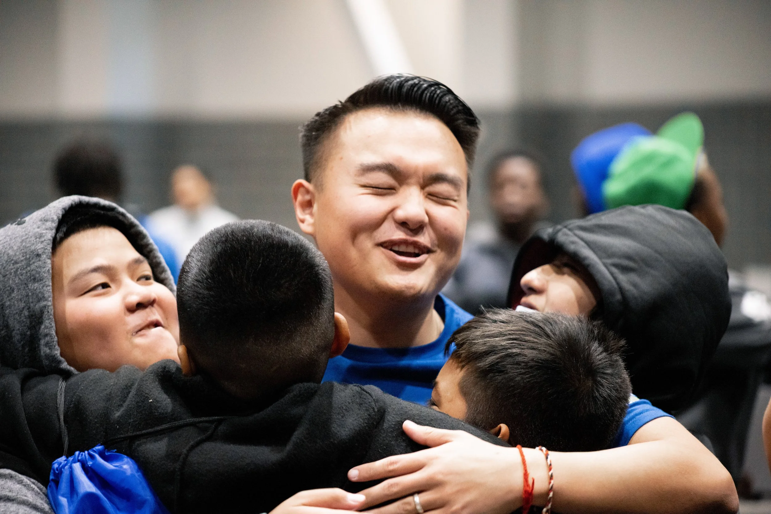 A group of young people hugging in celebration, with one person smiling broadly in the center.