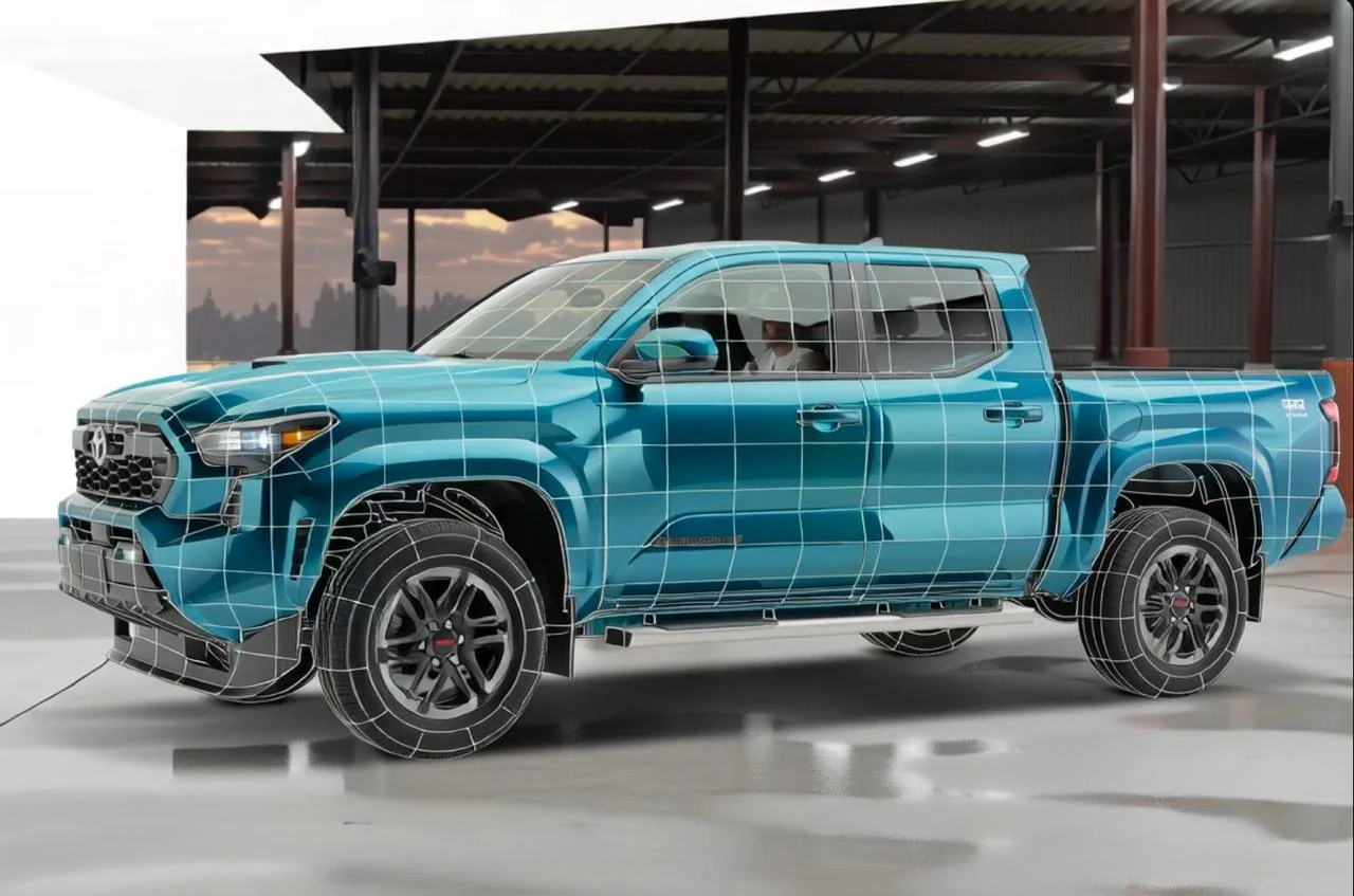 Camión azul en producción, con malla de digitalización sobre la carrocería y ruedas, en un taller con techo metálico y cielo al fondo.