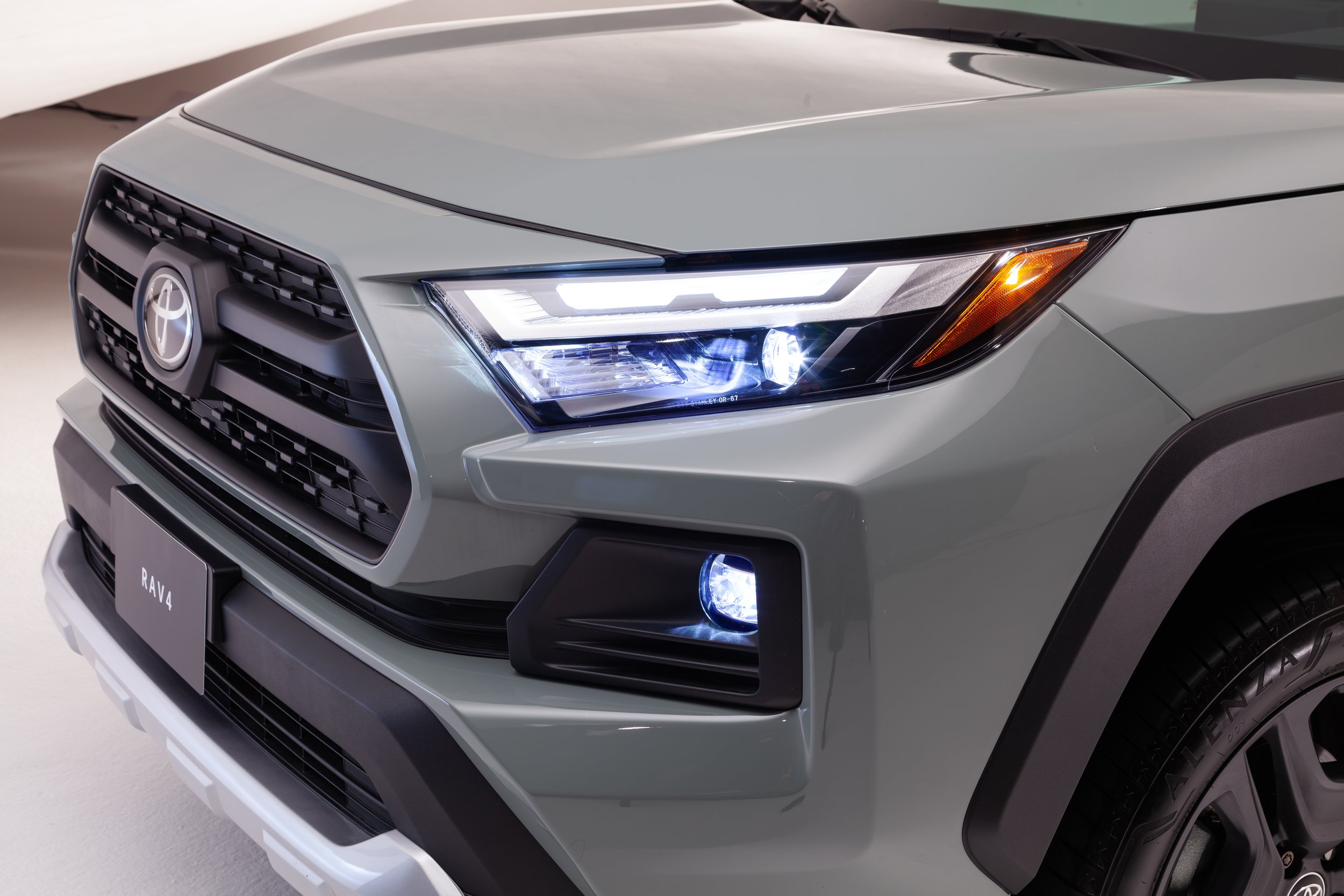Frontal de un automóvil Toyota RAV4, color gris con faros LED, luces antiniebla y parrilla negra.
