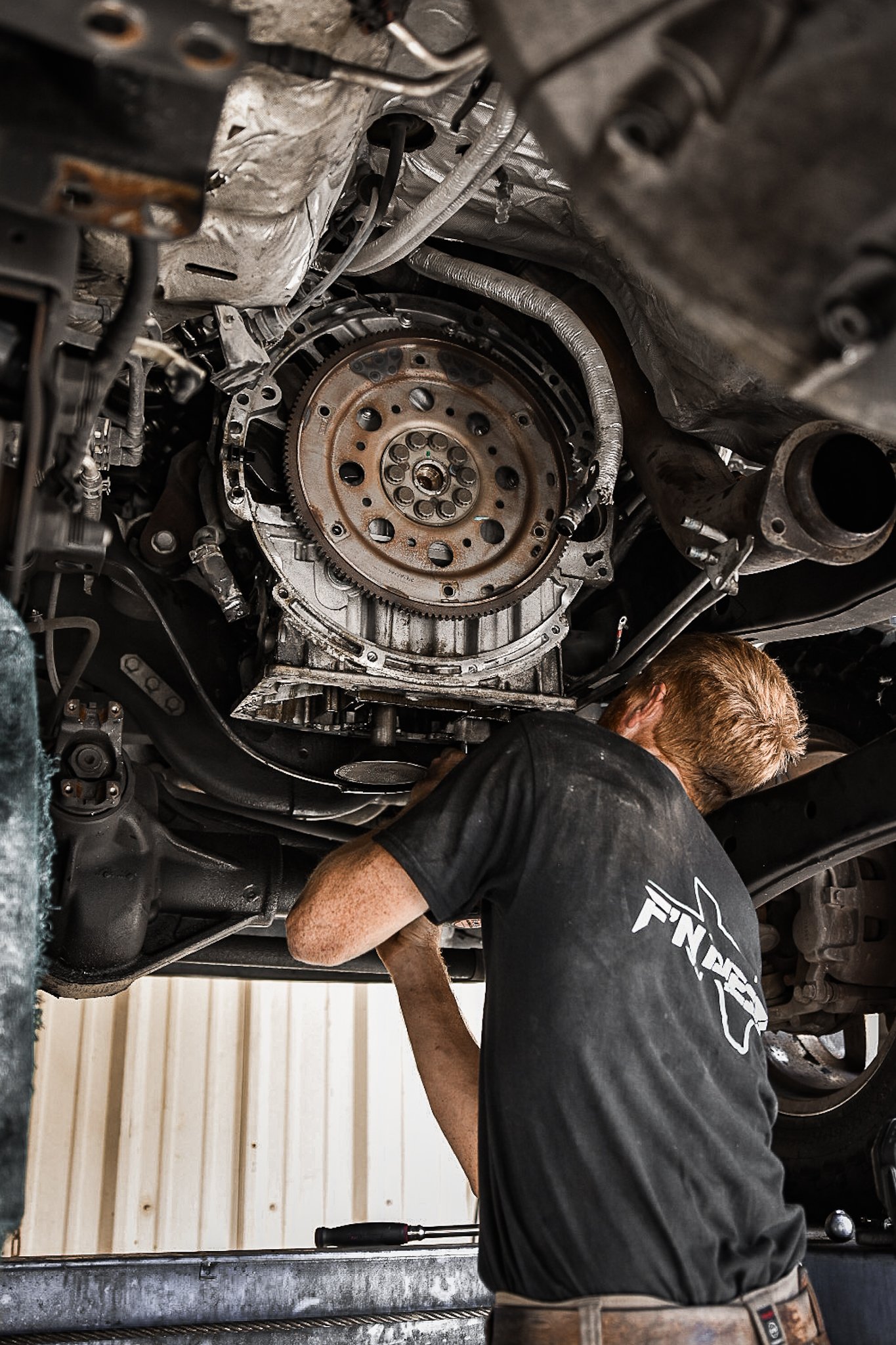 A mechanic working underneath a car, inspecting or repairing the engine.