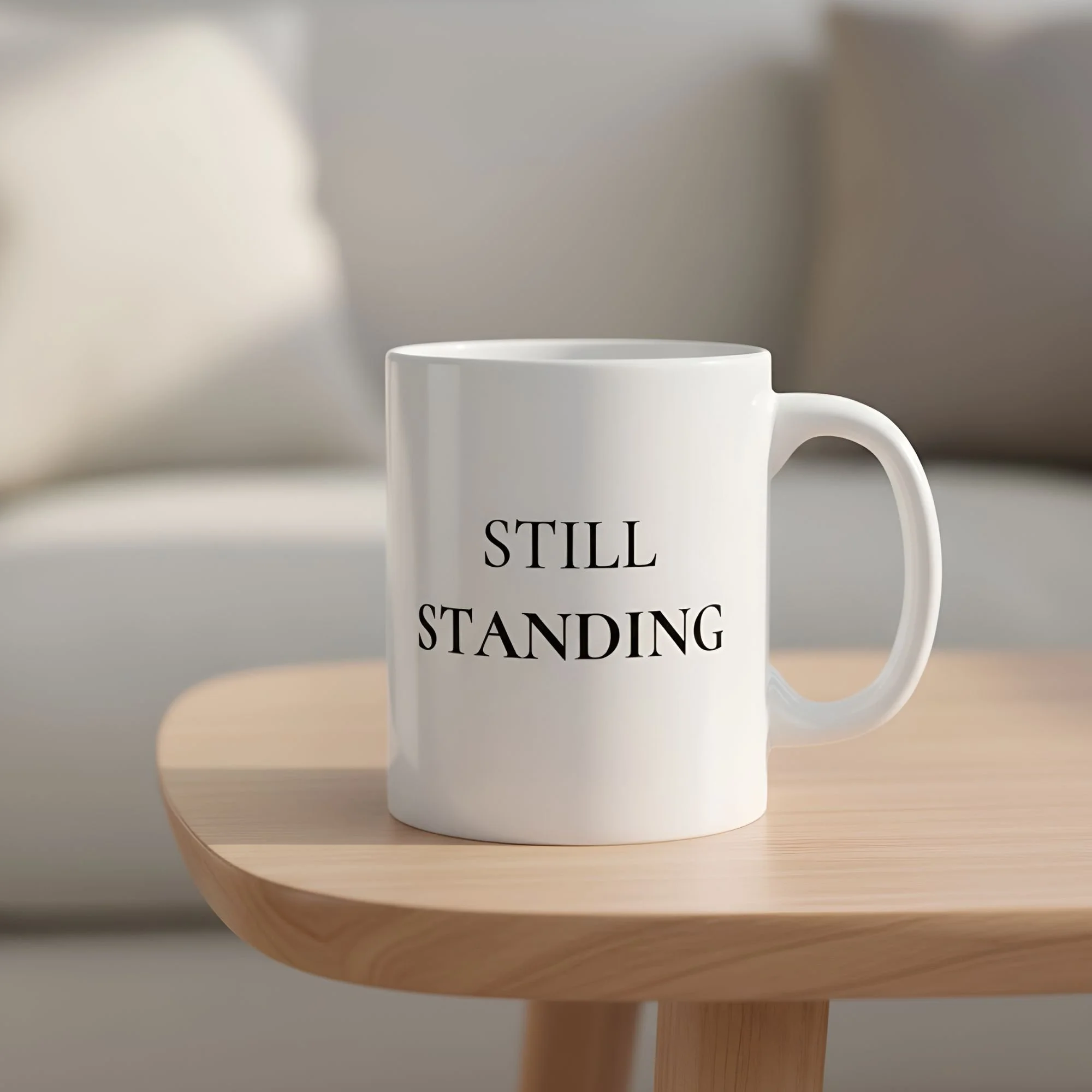 Still Standing 11oz white ceramic mug resting on a side table