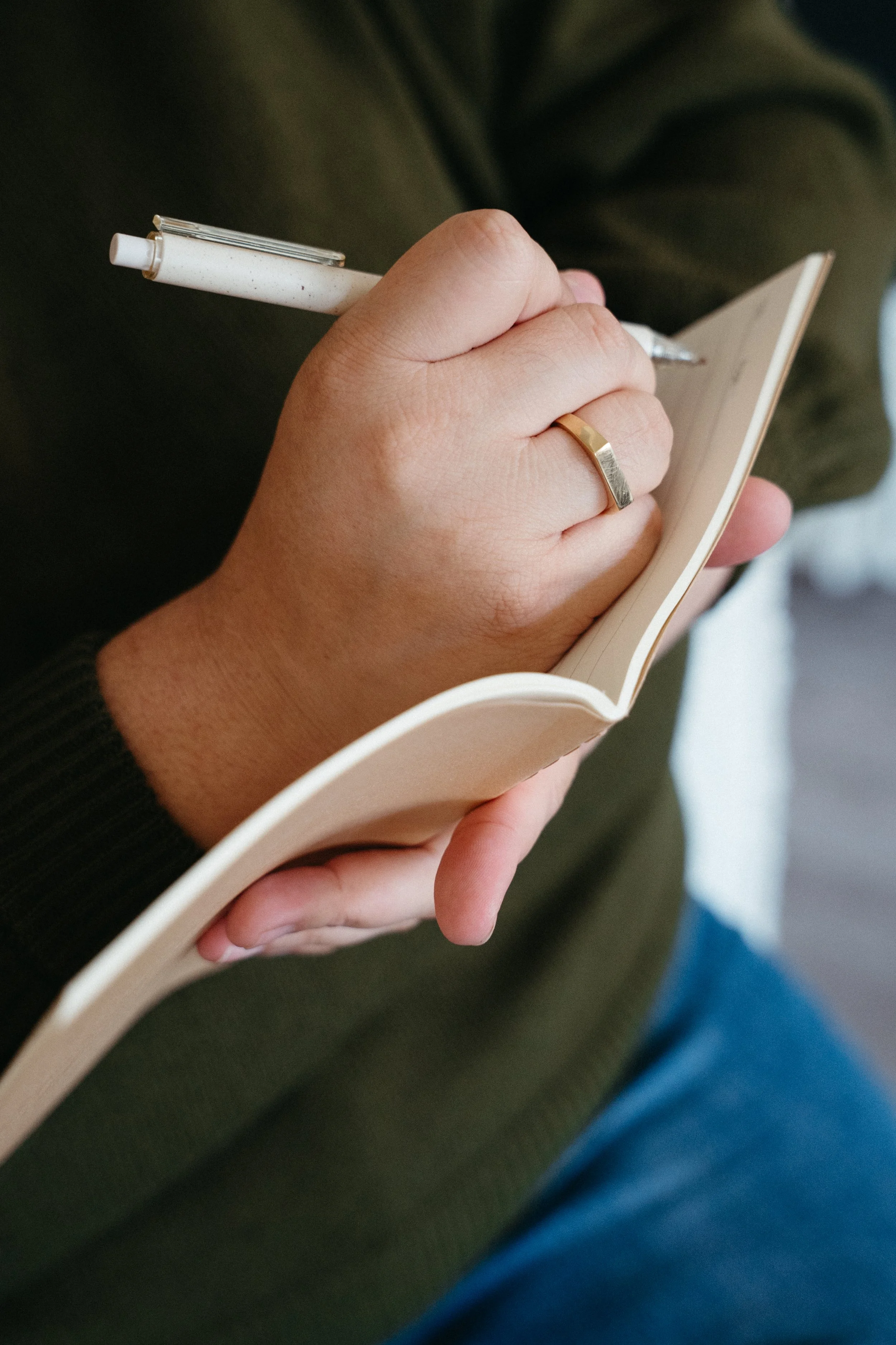 Up close photo of a hand with a gold ring about to write in a lined notebook