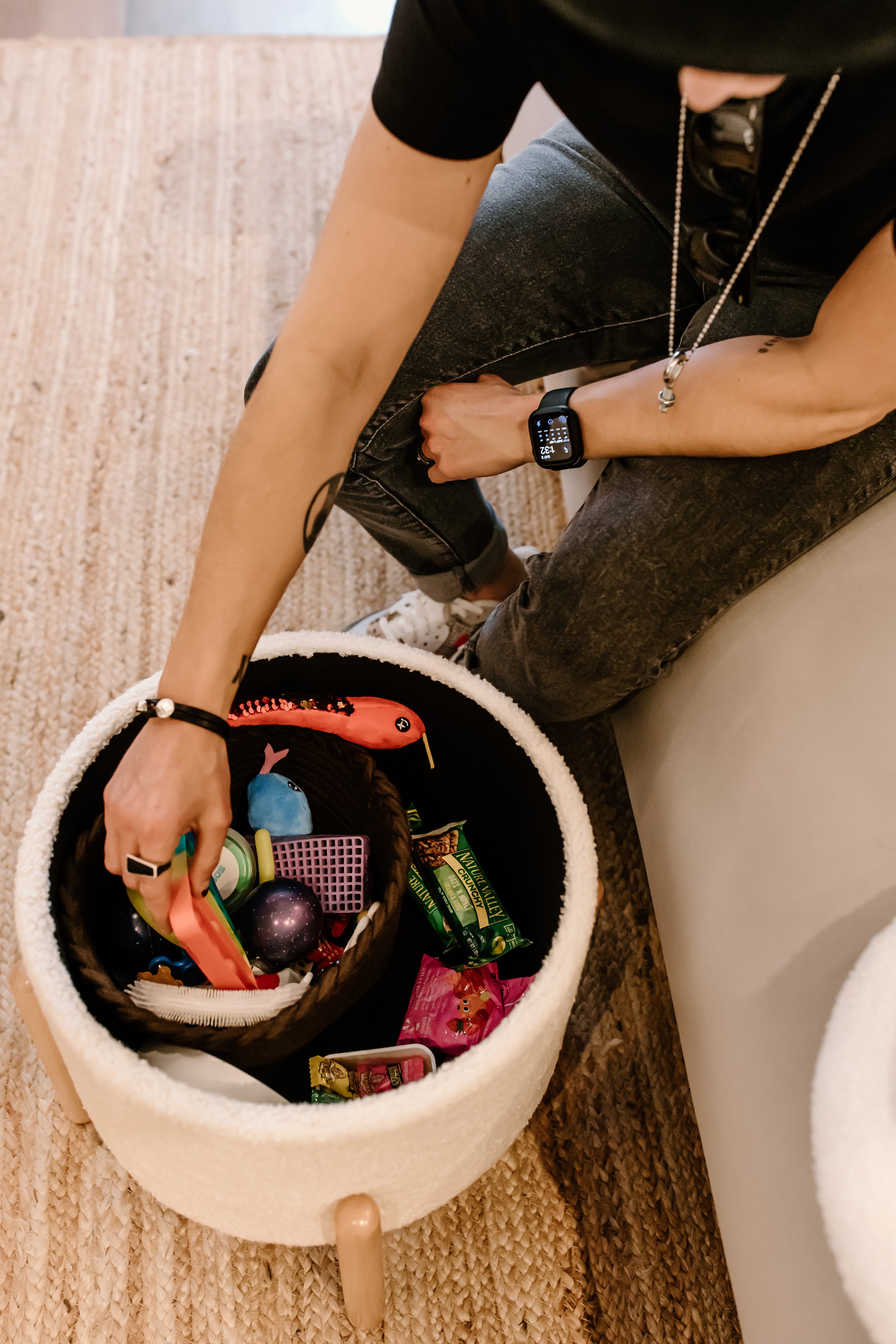 Photo from above of an arm reaching for a basket of neurodivergent stim toys