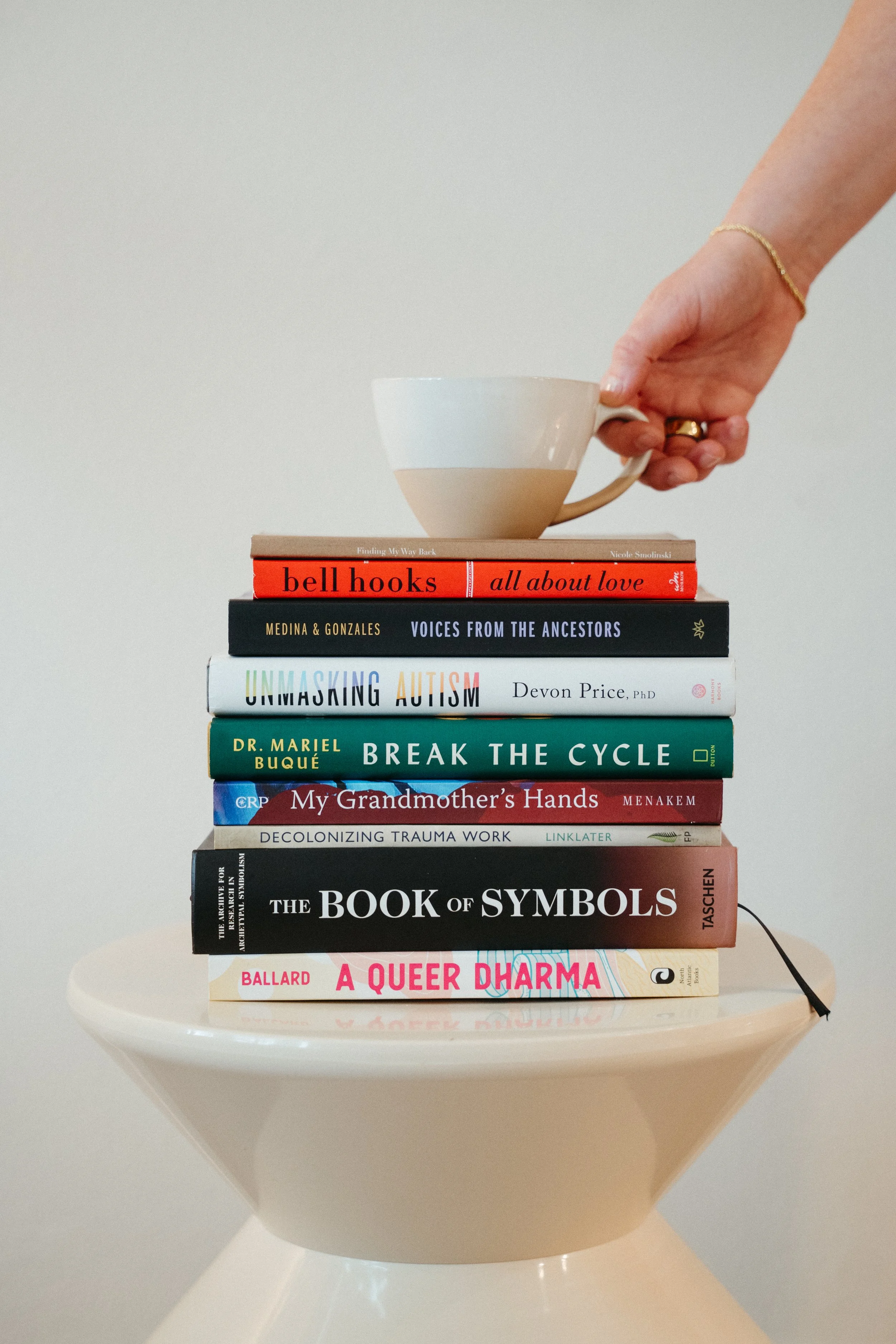 Photo of hand holding a teacup perched on top of a stack of books in the Nido office
